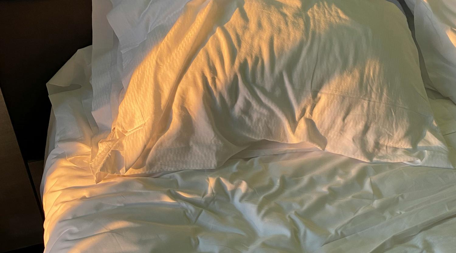 Weißes Kissen und Bettwäsche mit Sonnenlicht im Glockna Hotelzimmer