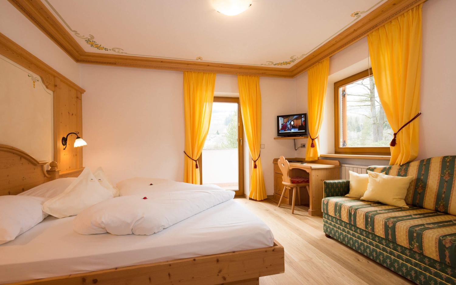 Gemütliches Zimmer im Hotel Weiher mit Holzmöbeln und gelben Vorhängen