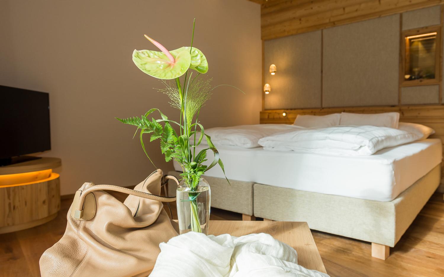 Hotel Weiher Zimmer mit gemütlichem Bett, Pflanzen und Holzdekor