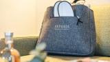 Filztasche des Hotel Arpuria mit weißen Hausschuhen auf einem Sofa