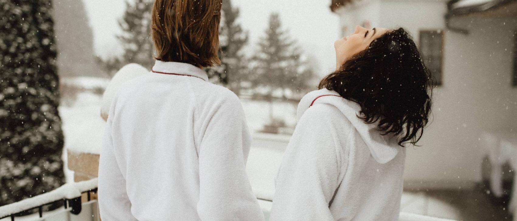 Paar im Bademantel auf Balkon im Schnee im Schlosshotel Kitzbühel