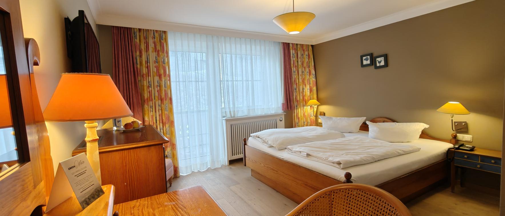 Gemütliches Zimmer im Sport- und Wellnesshotel Angerhof ****S mit Doppelbett und Holzmöbeln