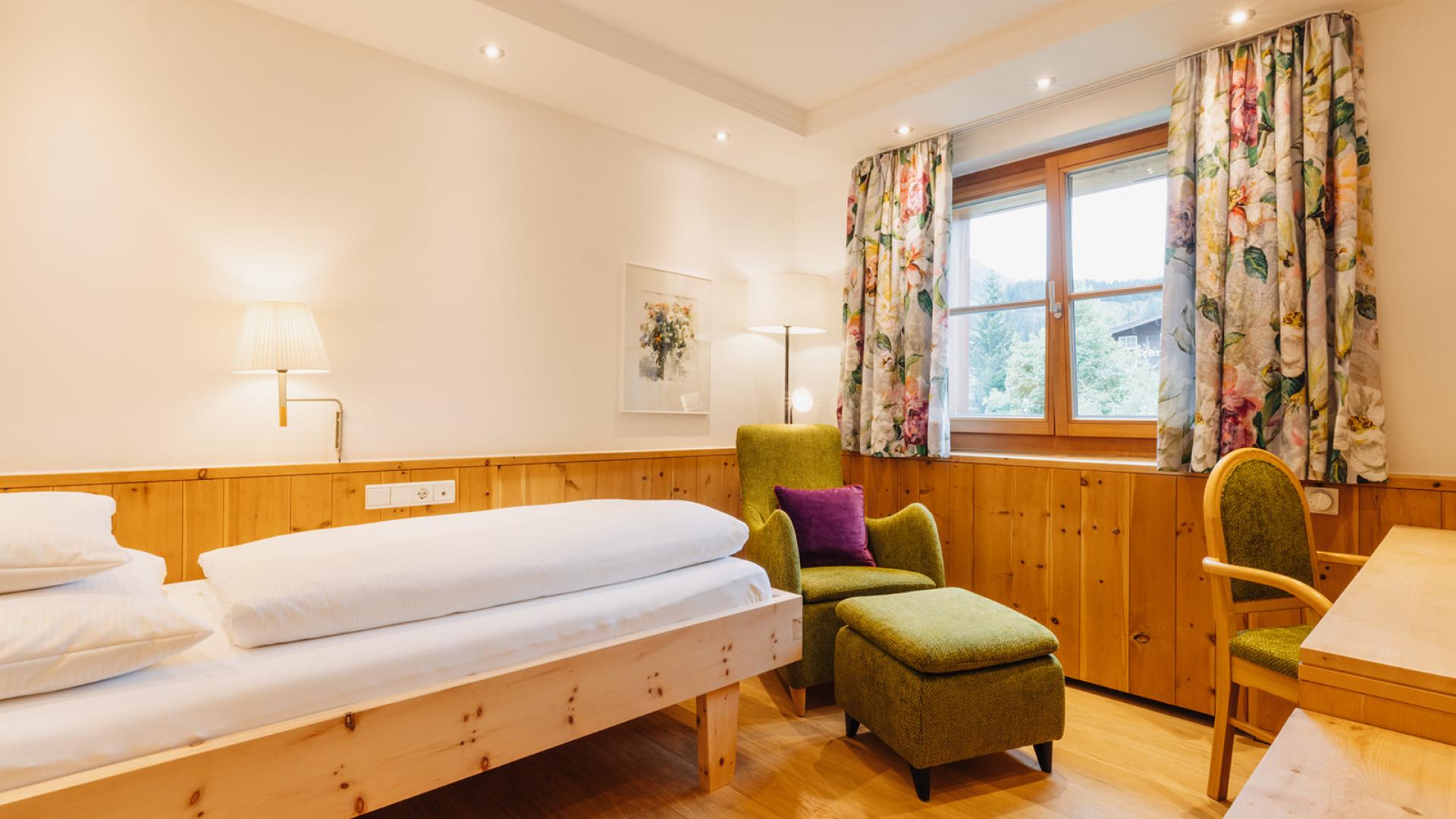 Gemütliches Zimmer im Hotel Aurora mit Holzdekor und einem grünen Sessel