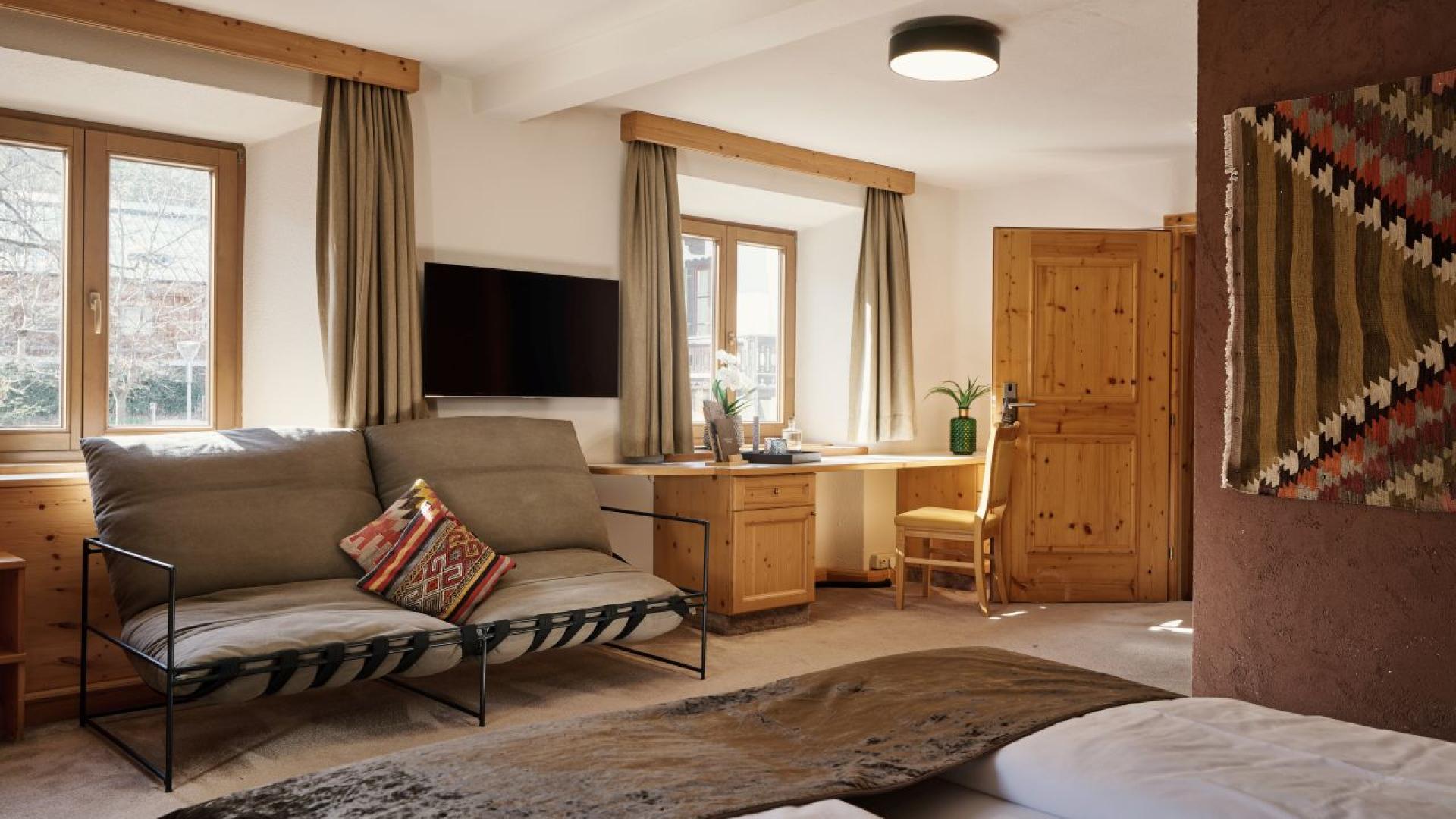 Gemütliches Zimmer im Hotel MOHR life resort mit Sofa, Schreibtisch und Naturholzböden.
