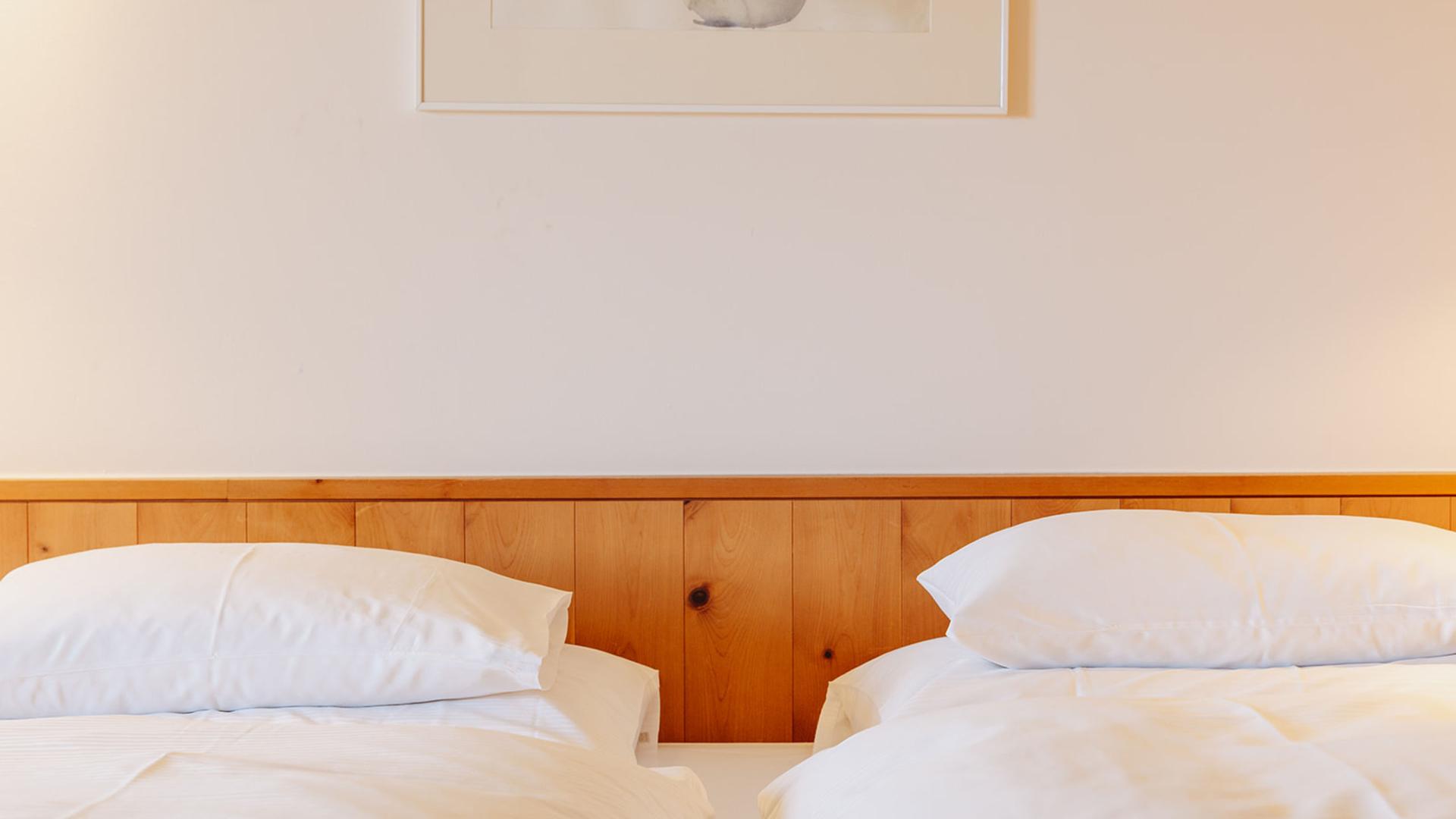 Zwei Einzelbetten im Hotel Aurora mit Holzverkleidung und weißer Bettwäsche
