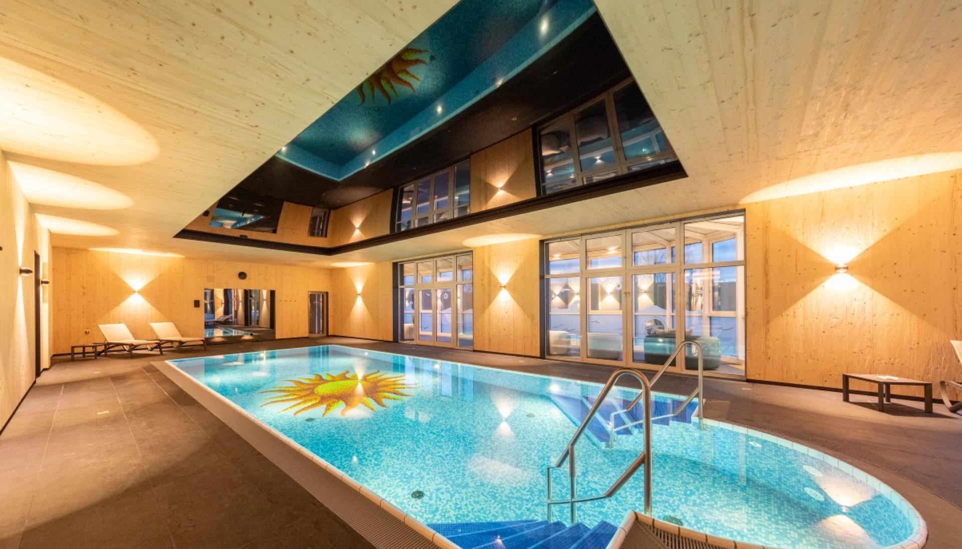 Innenpool im Fair Resort mit holzverkleideten Wänden und Sonnenmotiv im Wasser