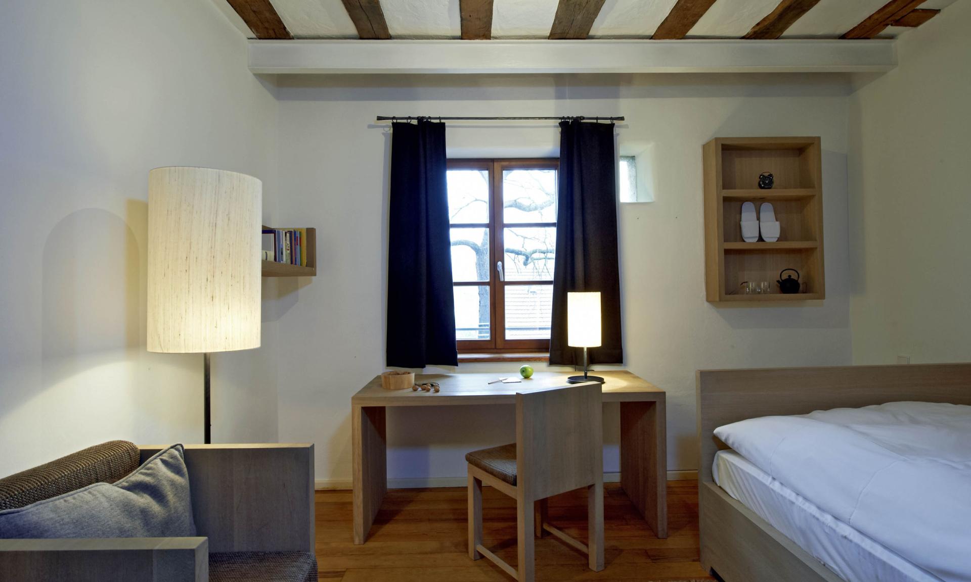 Einfaches Zimmer mit Schreibtisch und Bett im Kloster Hornbach