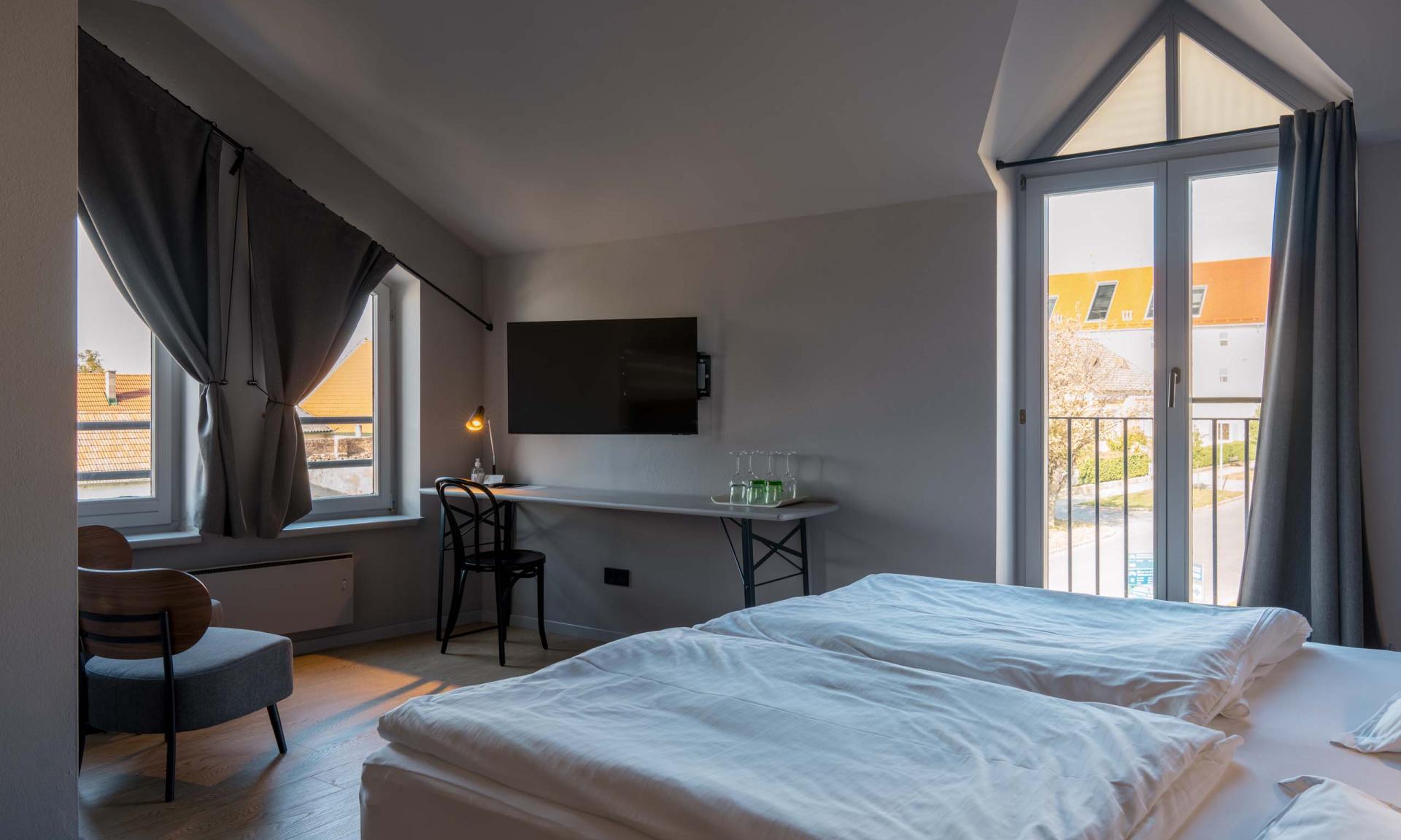 Hotelzimmer Luis v. Weyden mit Bett, Schreibtisch und Fenster mit Vorhängen