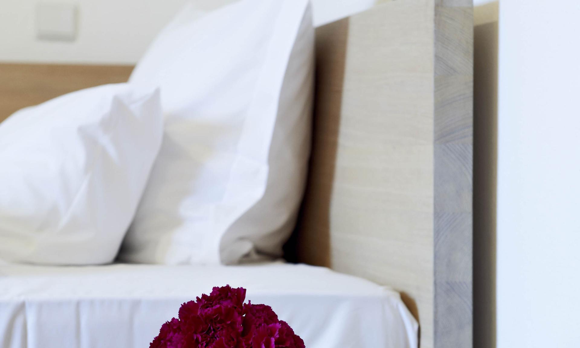 Schlichtes Zimmer im Kloster Hornbach mit Kreuz, Rosen und Buch auf Nachttisch