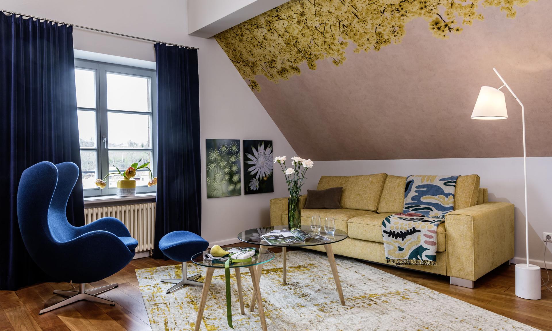 Helles Gästezimmer mit grünem Sessel und Bett im Kloster Hornbach