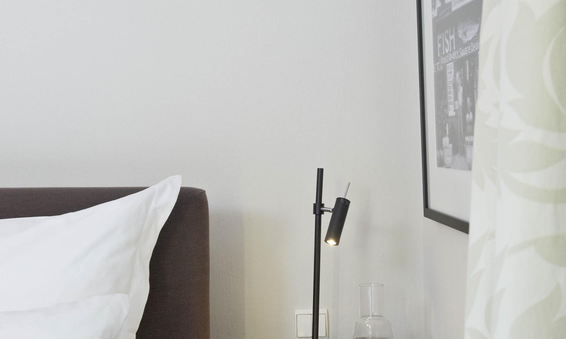 Schlafzimmer mit Bett und Lösch-förmigem Nachttisch mit Lampe