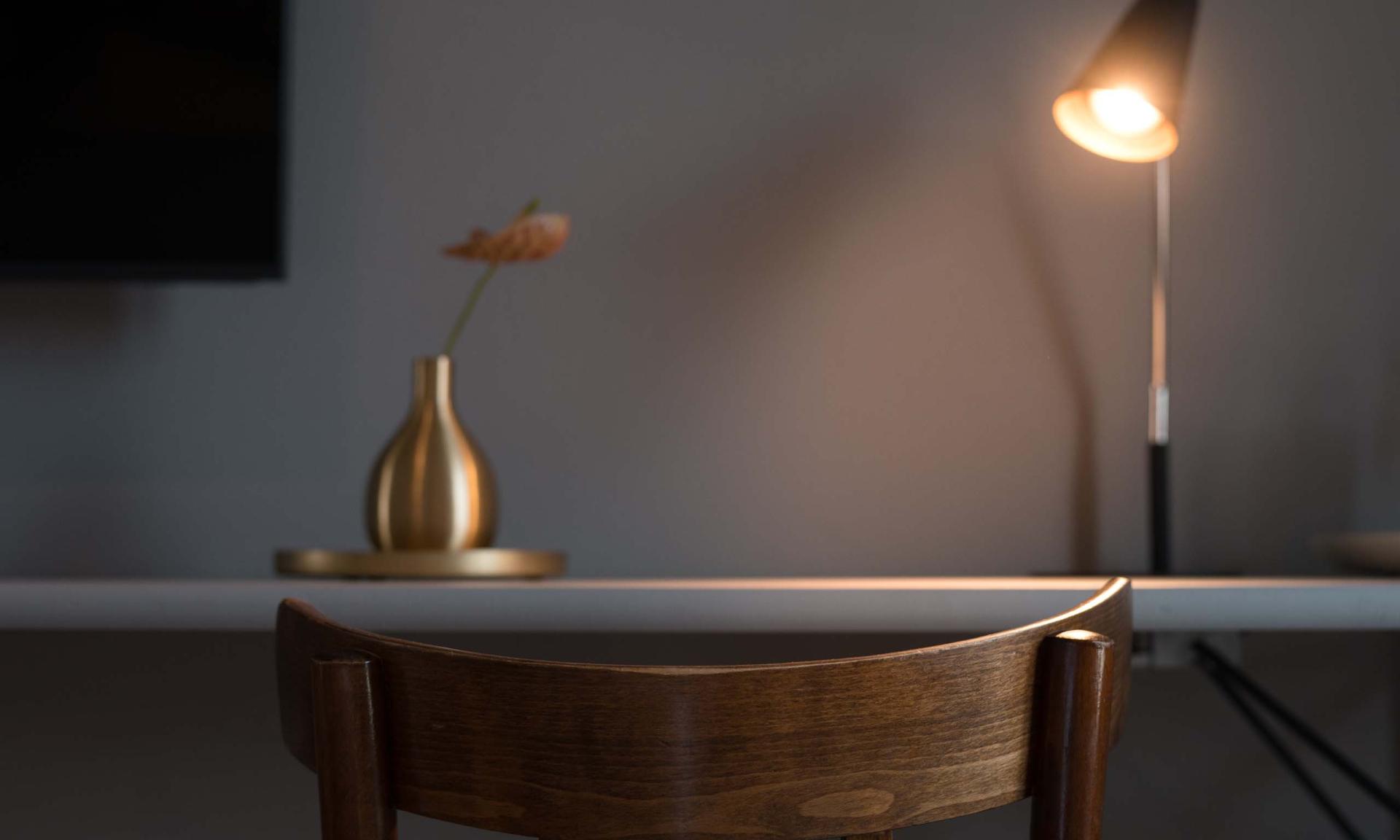 Luis v. Weyden Arbeitsplatz mit Holzstuhl, Lampe und goldener Vase