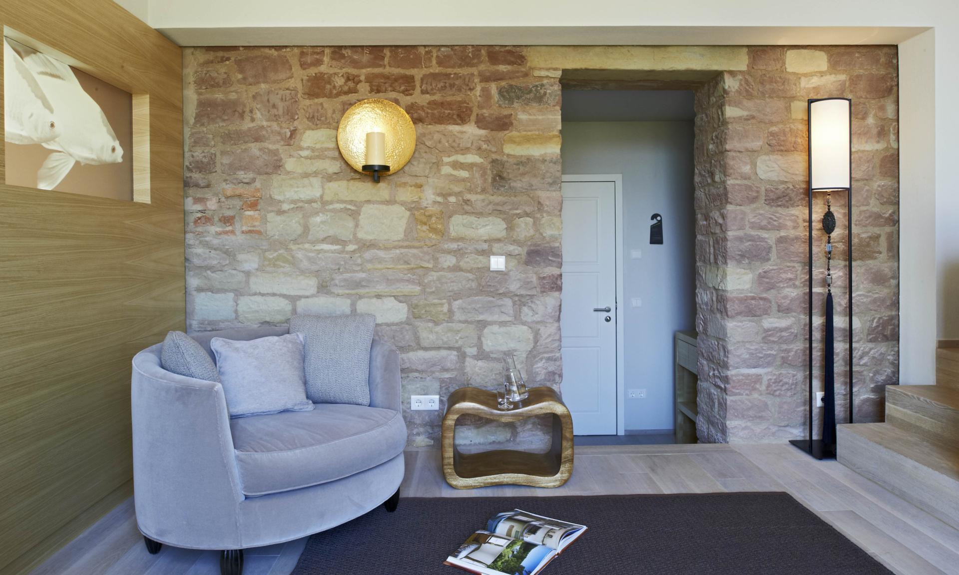 Heller Wohnbereich mit Lösch-Lampe an rustikaler Steinwand und grauem Sessel