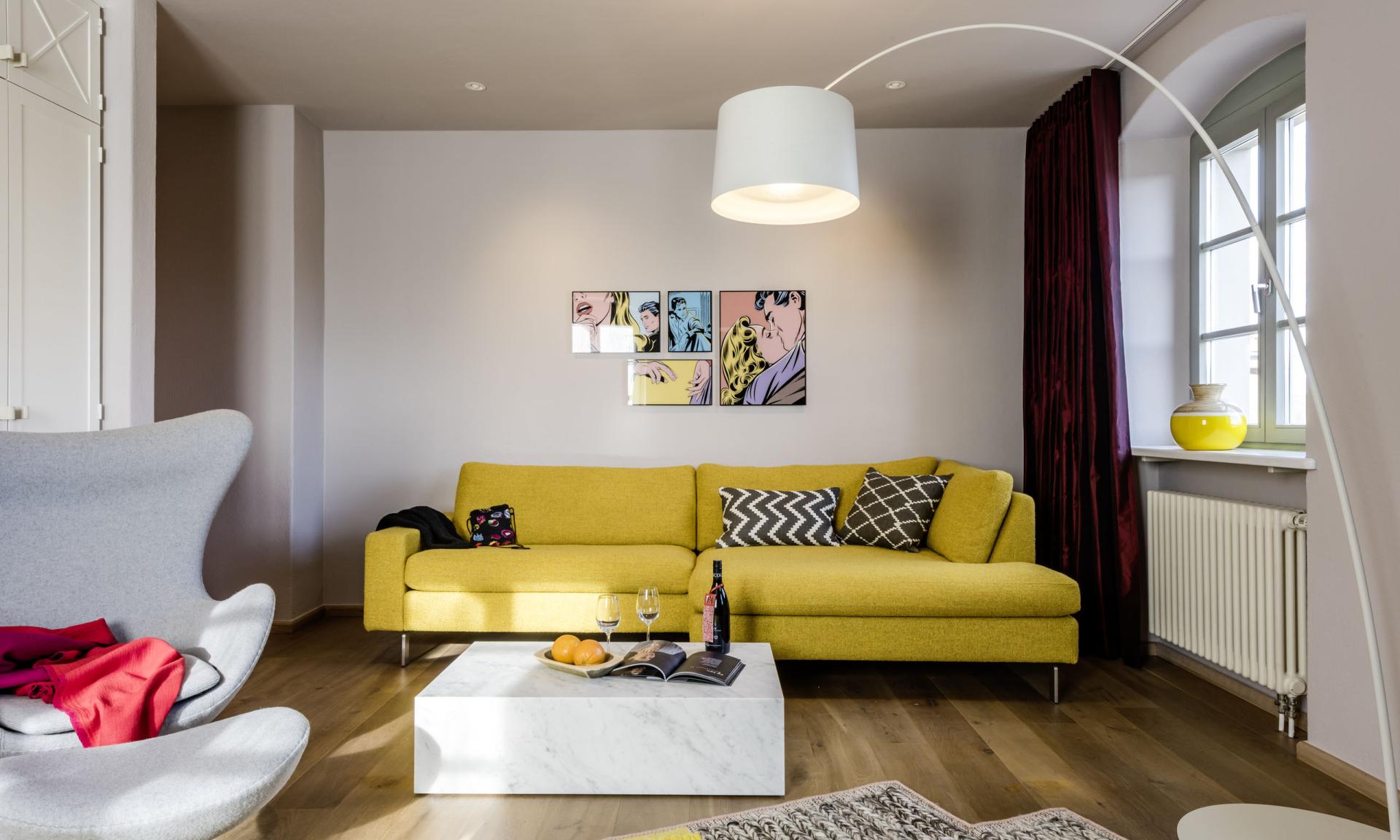 Modern eingerichtetes Wohnzimmer im Kloster Hornbach mit gelbem Sofa und weißem Sessel
