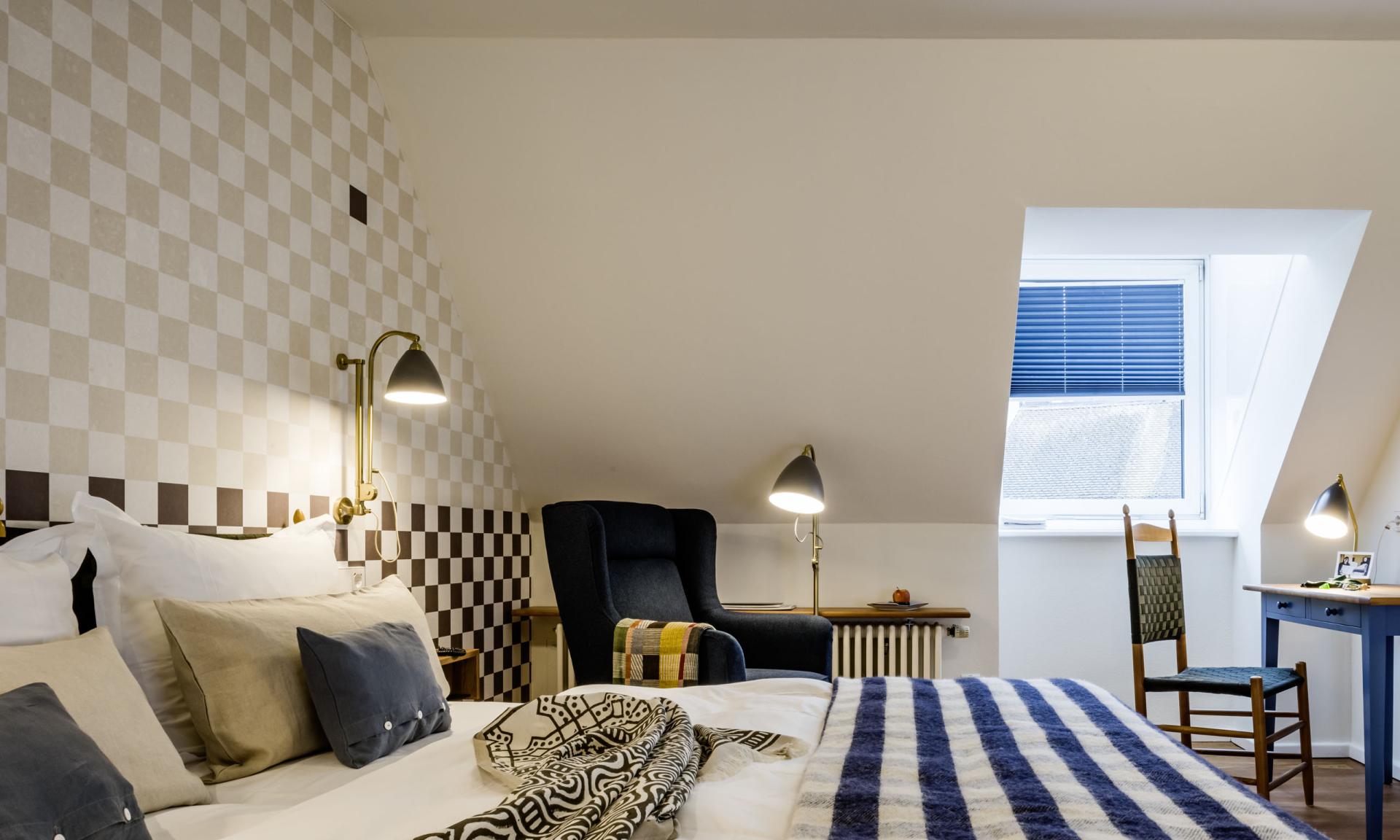 Gemütliches Zimmer im Kloster Hornbach mit Bett, Sessel und Schreibtisch