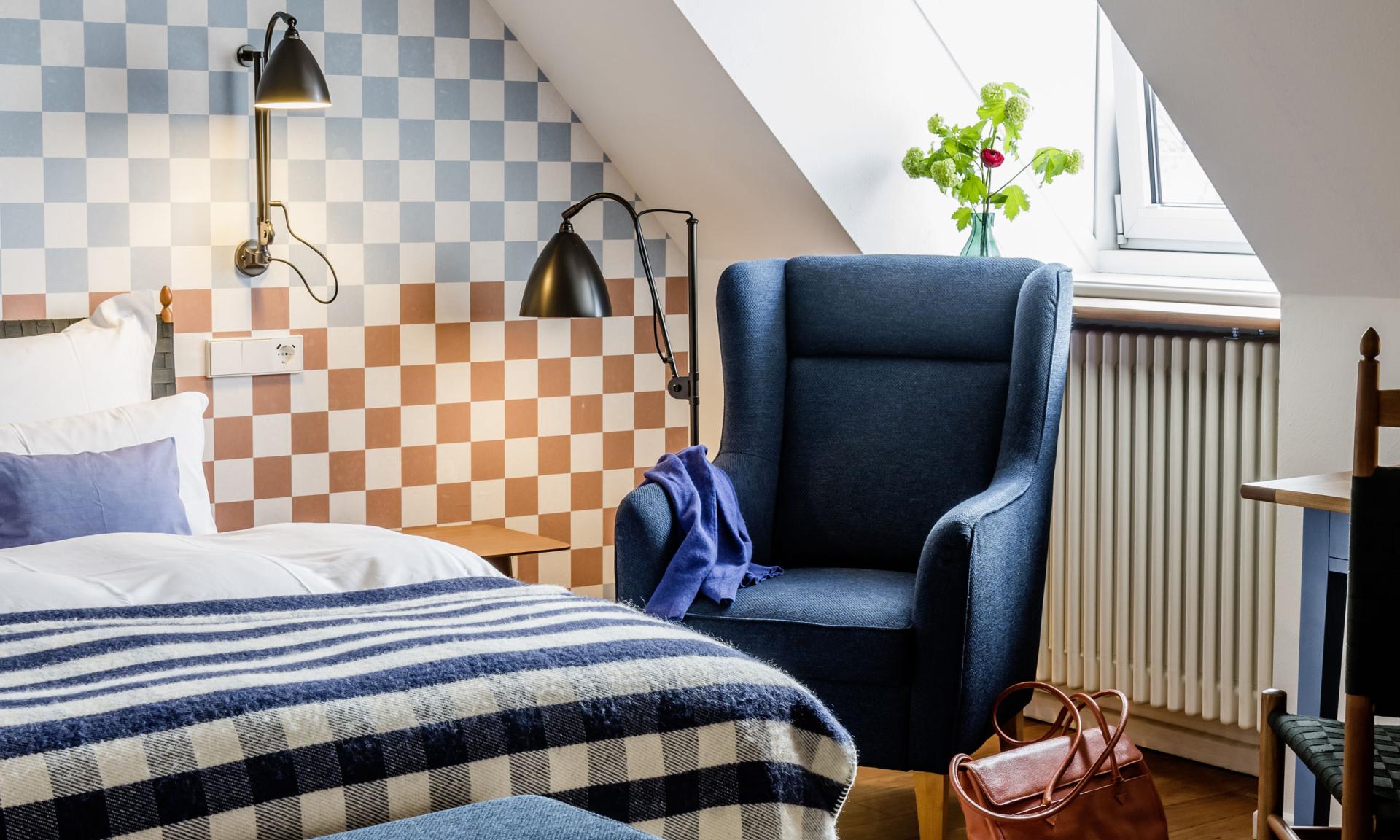 Gemütliches Zimmer im Kloster Hornbach mit kariertem Wandmuster und blauer Sitzgruppe