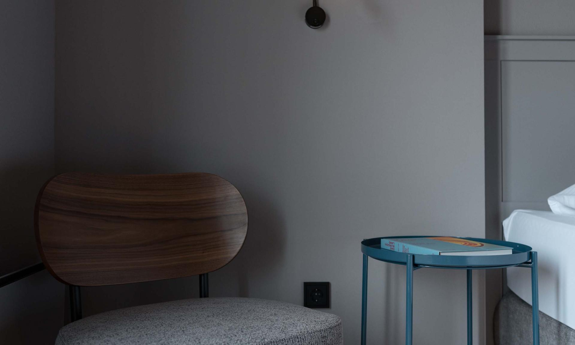 Luis v. Weyden Sessel, Nachttisch und Wandlampe in modernem Schlafzimmer