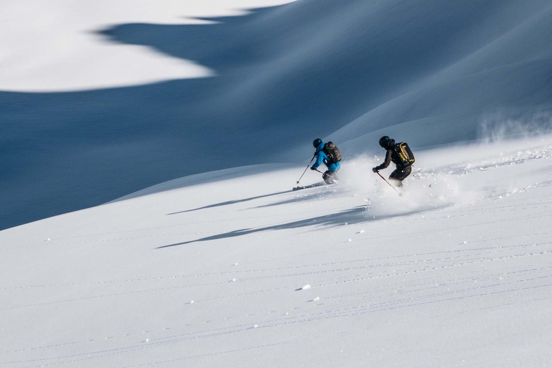 Zwei Skifahrer fahren bei Hotel Aurora über frischen Pulverschnee