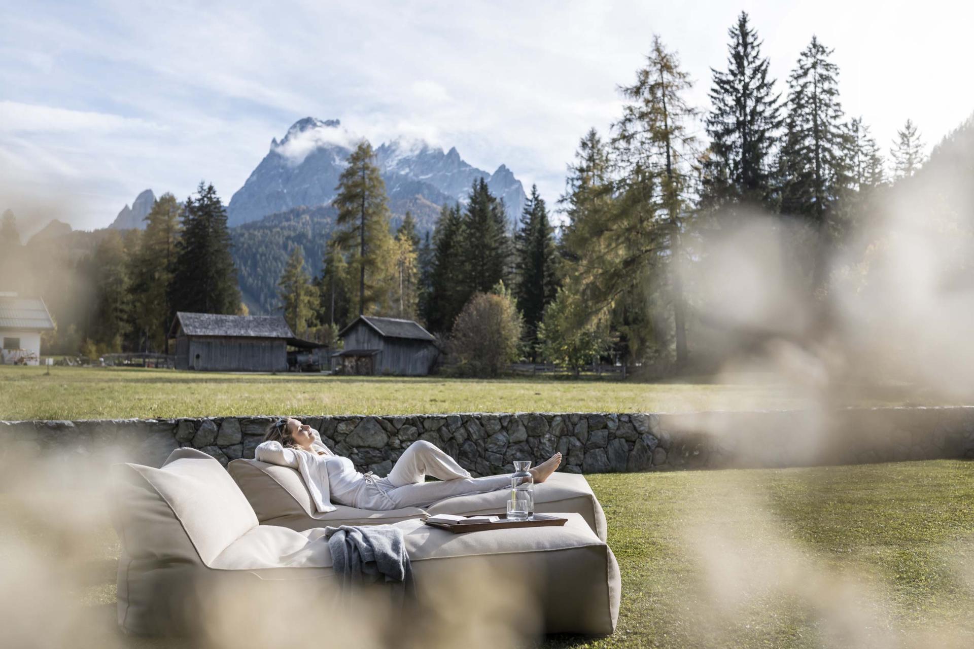 Entspannte Person auf Sofa mit Bergblick im Garten des Hotel Monika