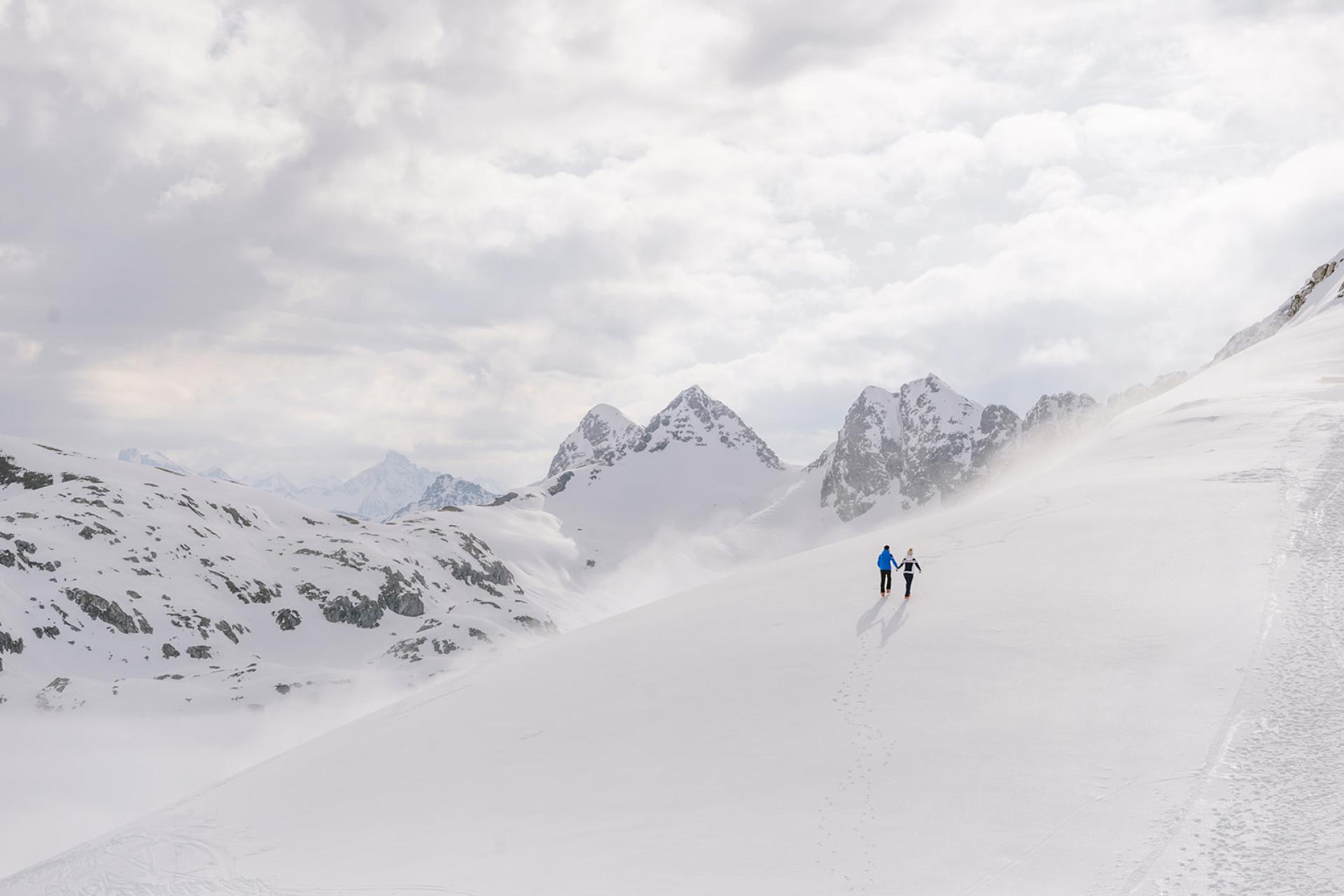 Zwei Personen wandern im Schnee mit Bergen im Hintergrund Hotel Aurora
