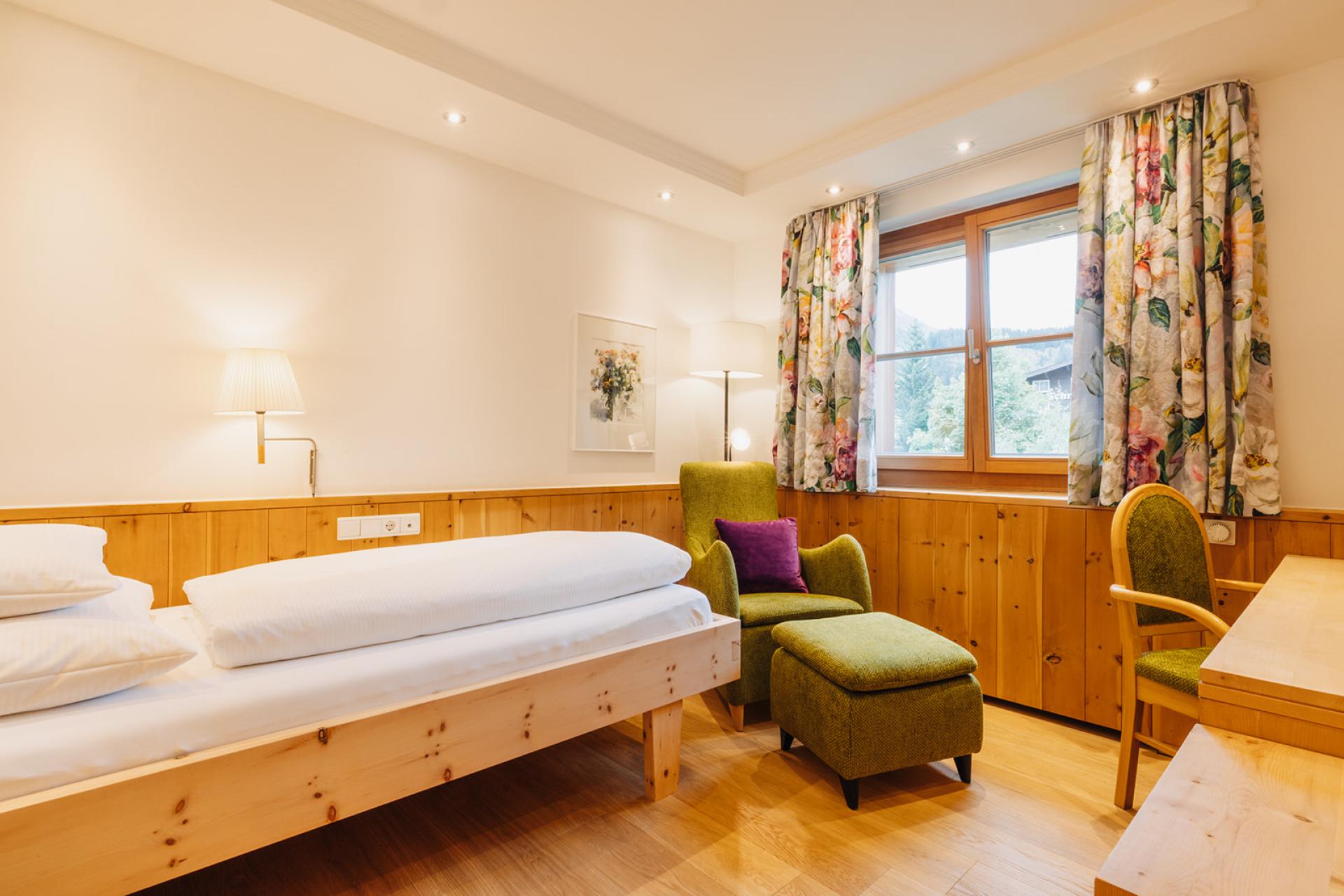 Gemütliches Zimmer im Hotel Aurora mit Holzdekor und einem grünen Sessel