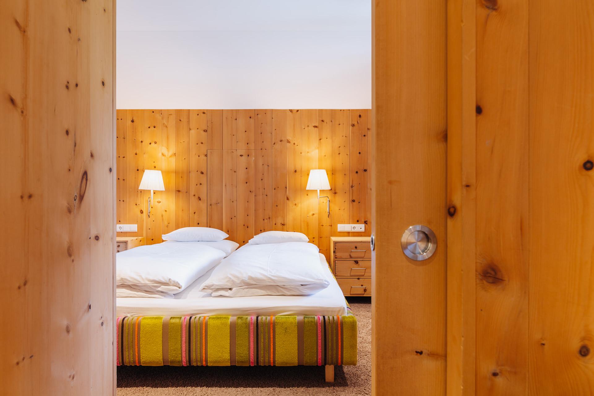 Gemütliches Doppelzimmer im Hotel Aurora mit Holzvertäfelung und warmem Licht