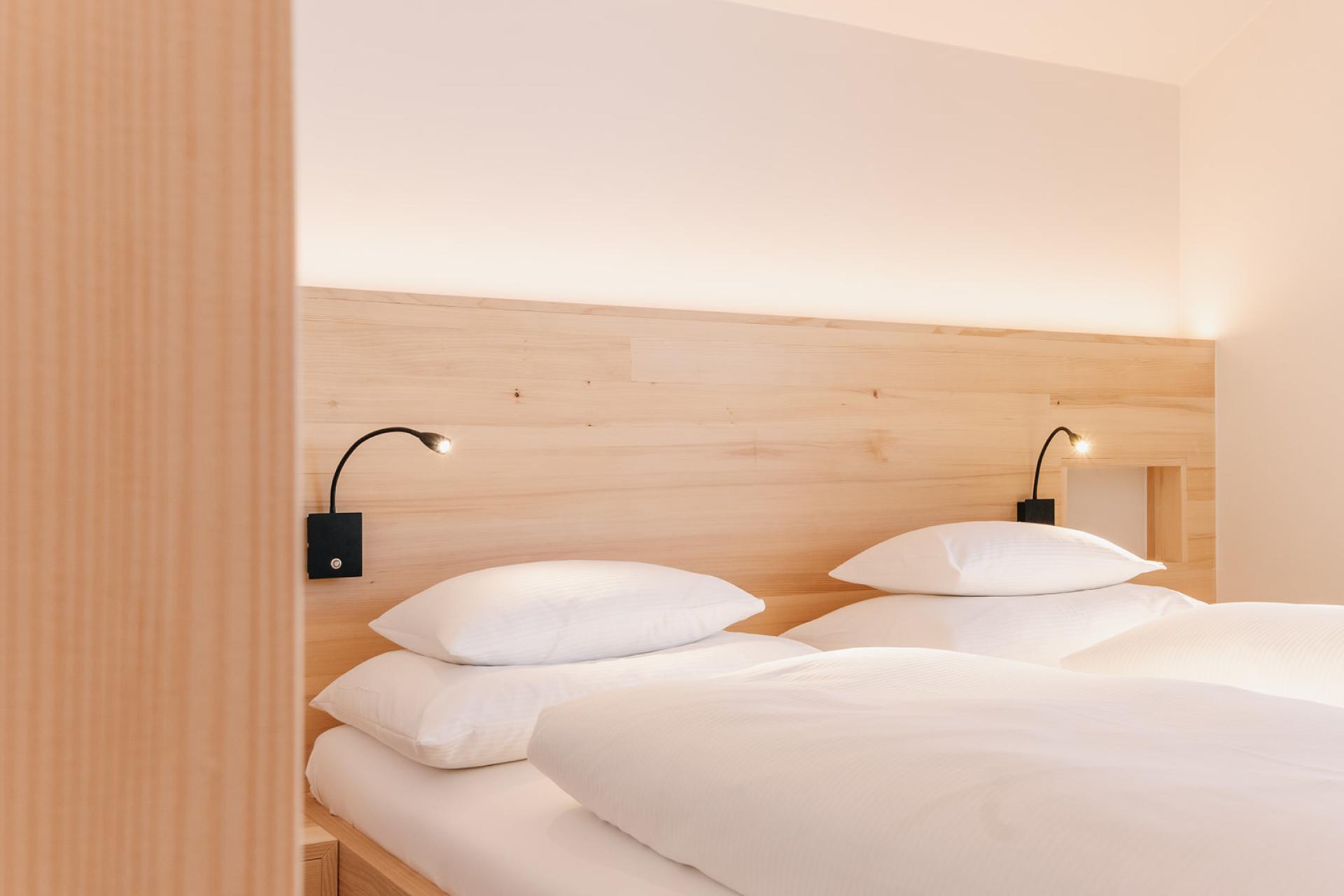 Schlafzimmer mit zwei Betten im Hotel Aurora mit Holzdekor und Leselampen