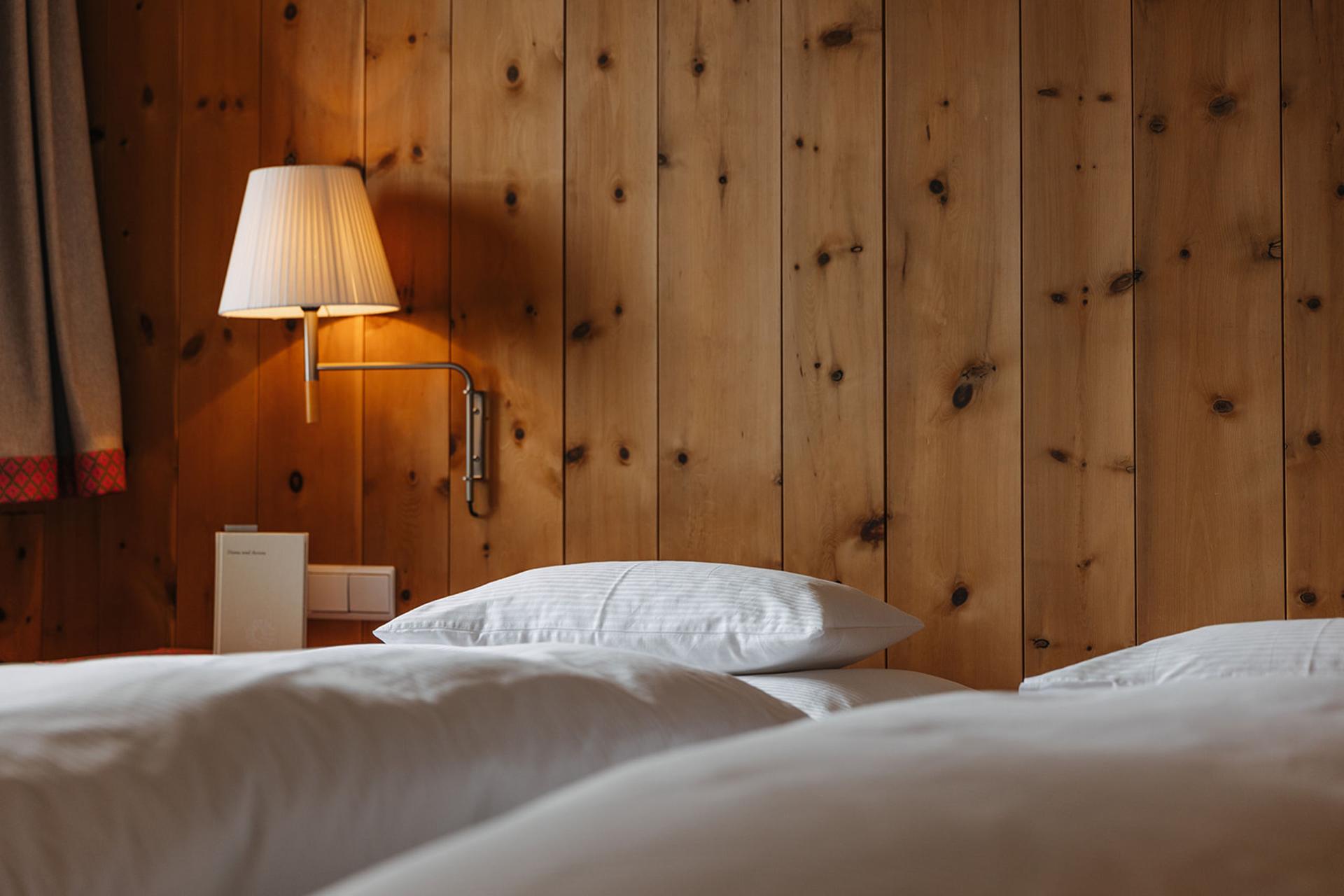 Gemütliches Hotelzimmer im Hotel Aurora mit Holzwand und weißer Bettwäsche