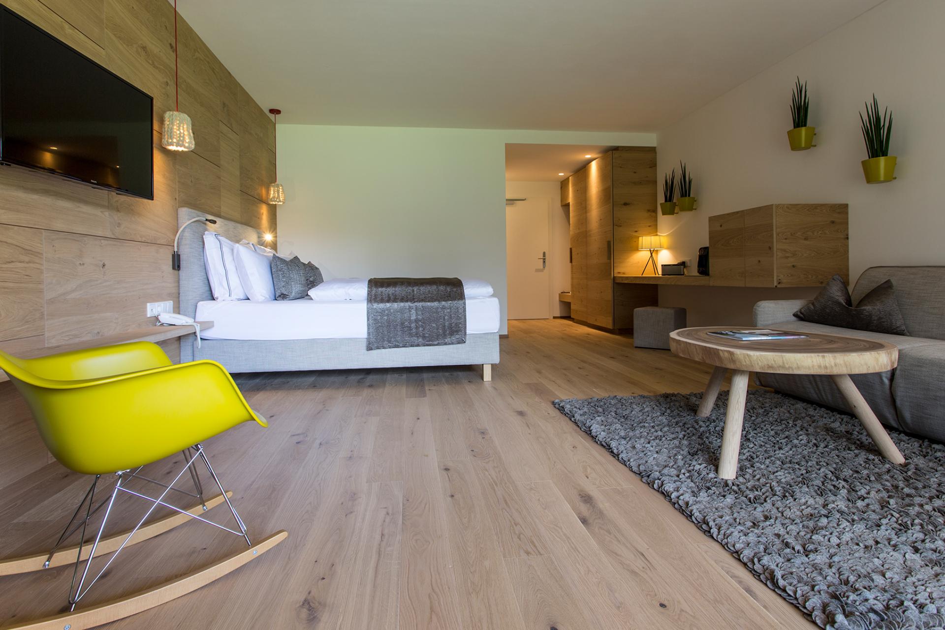 Modernes Hotelzimmer im Hotel Monika mit Bett, Sitzbereich und Holzdekoration