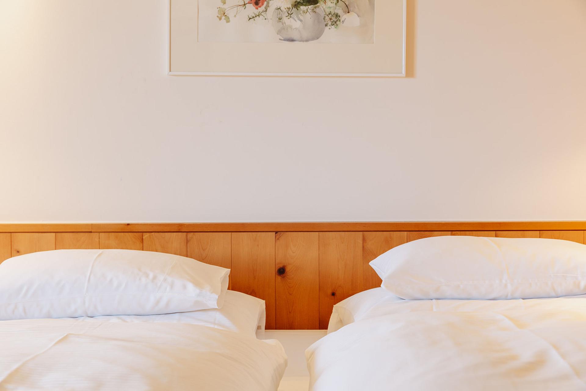 Zwei Einzelbetten im Hotel Aurora mit Holzverkleidung und weißer Bettwäsche