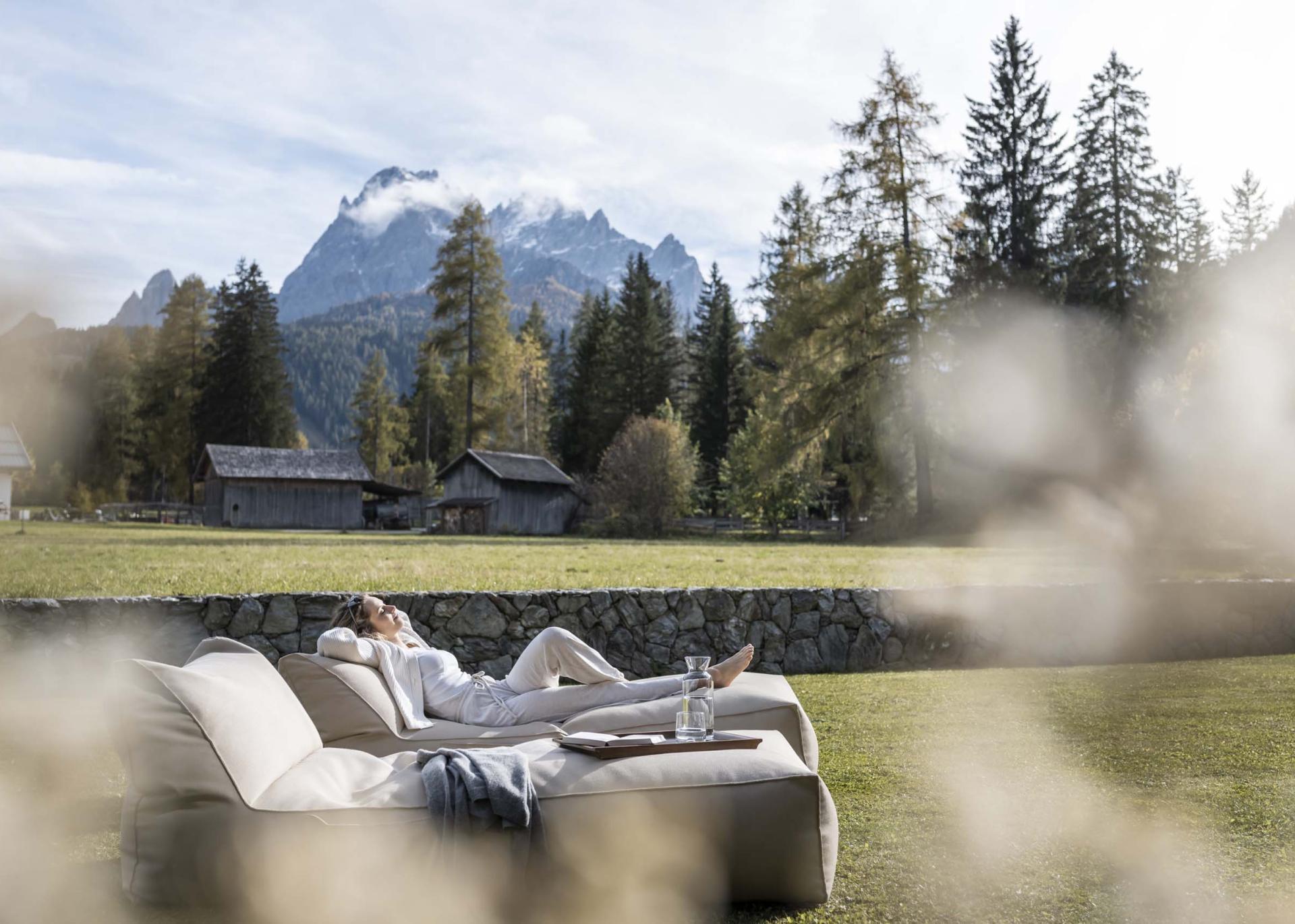 Entspannte Person auf Sofa mit Bergblick im Garten des Hotel Monika
