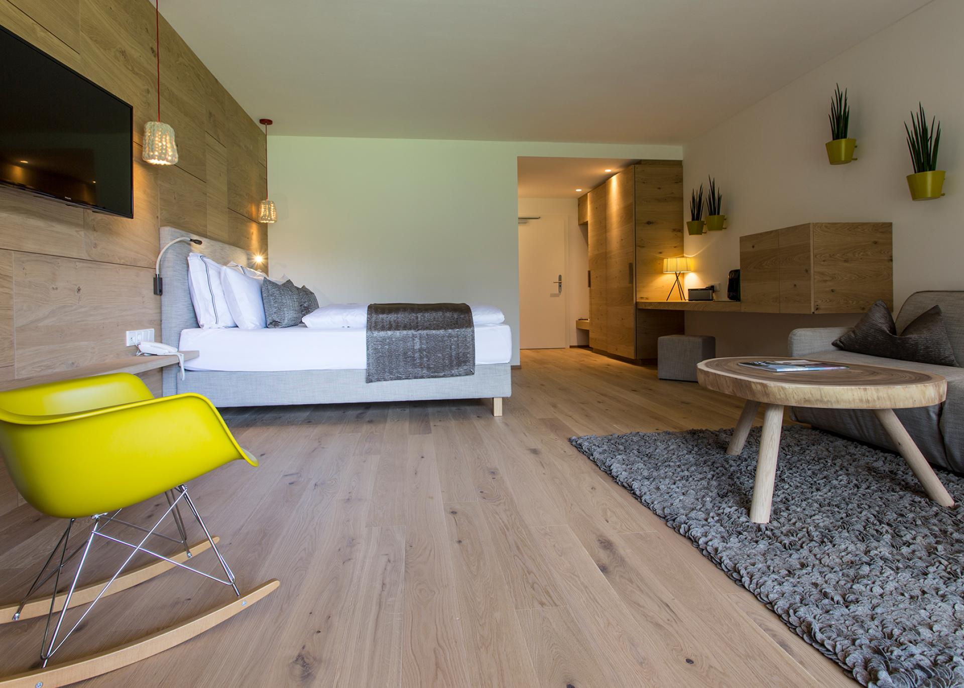 Modernes Hotelzimmer im Hotel Monika mit Bett, Sitzbereich und Holzdekoration