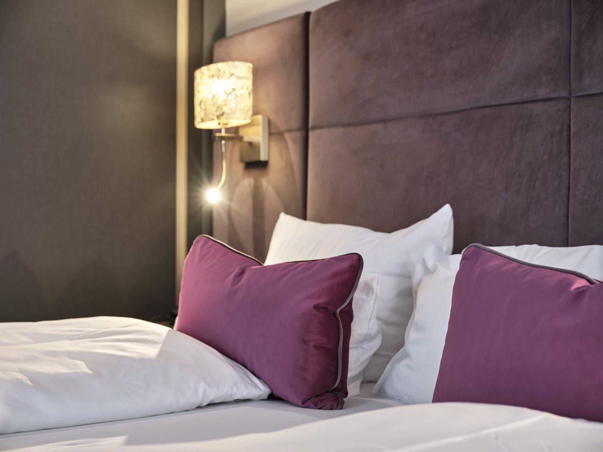 Bett mit weißen und violetten Kissen im Hotel Reppert
