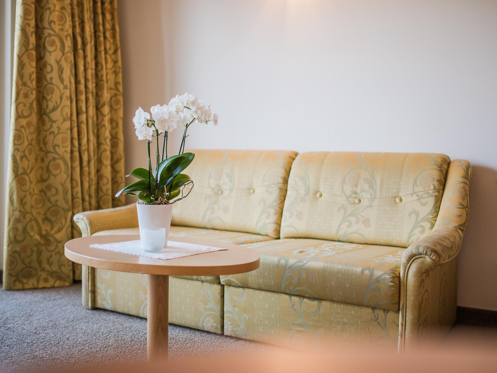Gemütliche Sitzecke im Alpenpalais Kröll mit Sofa und Blumentisch