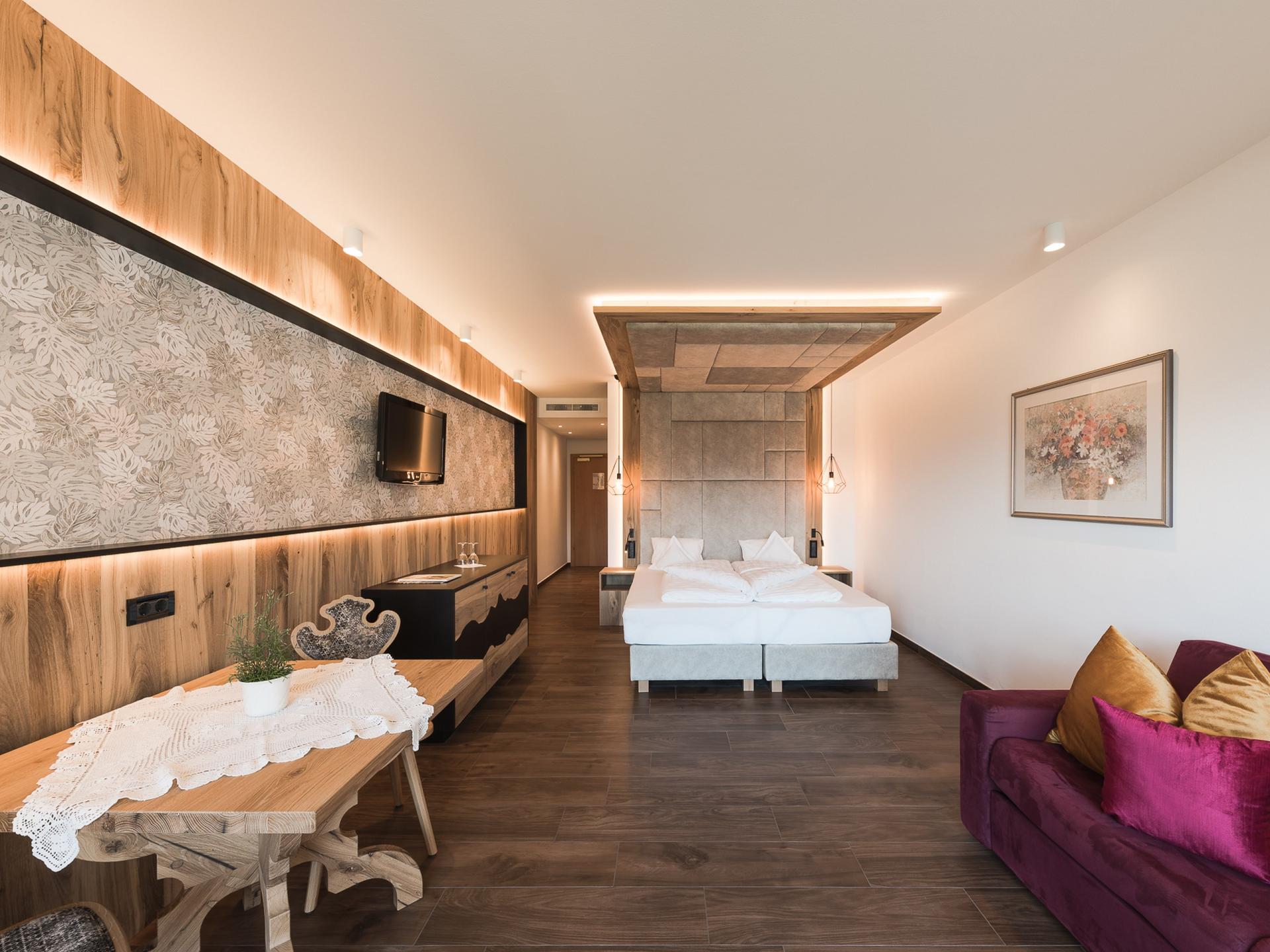 Modernes Hotelzimmer im Alpenpalais Kröll mit Doppelbett und Sitzbereich