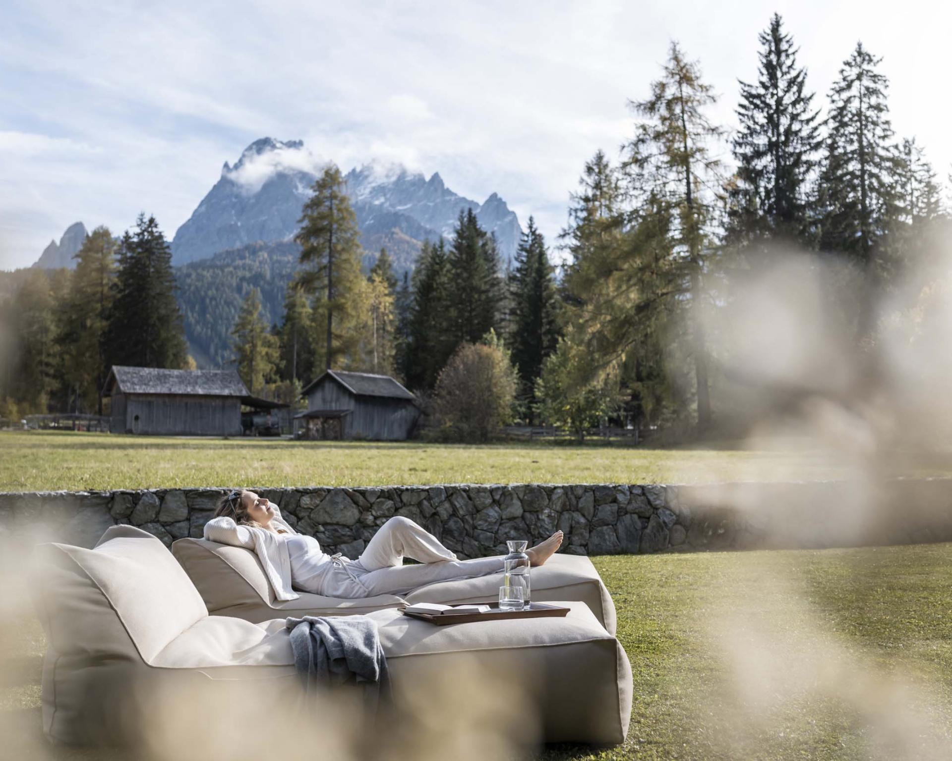 Entspannte Person auf Sofa mit Bergblick im Garten des Hotel Monika