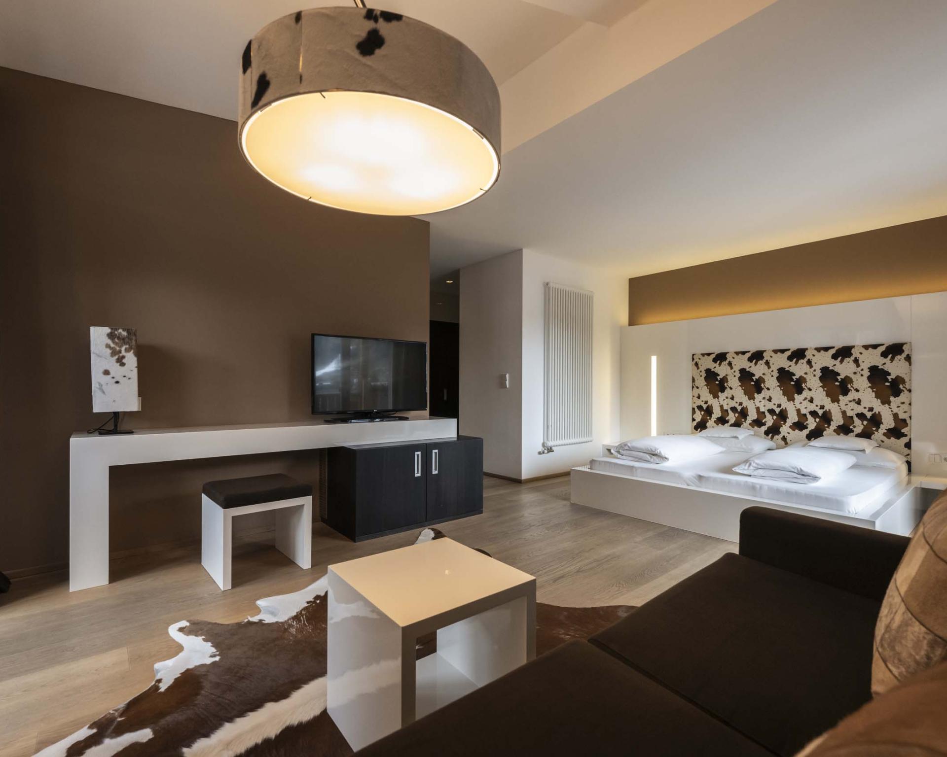 Modernes Zimmer im Hotel Monika mit Bett, Sofa und Beleuchtung