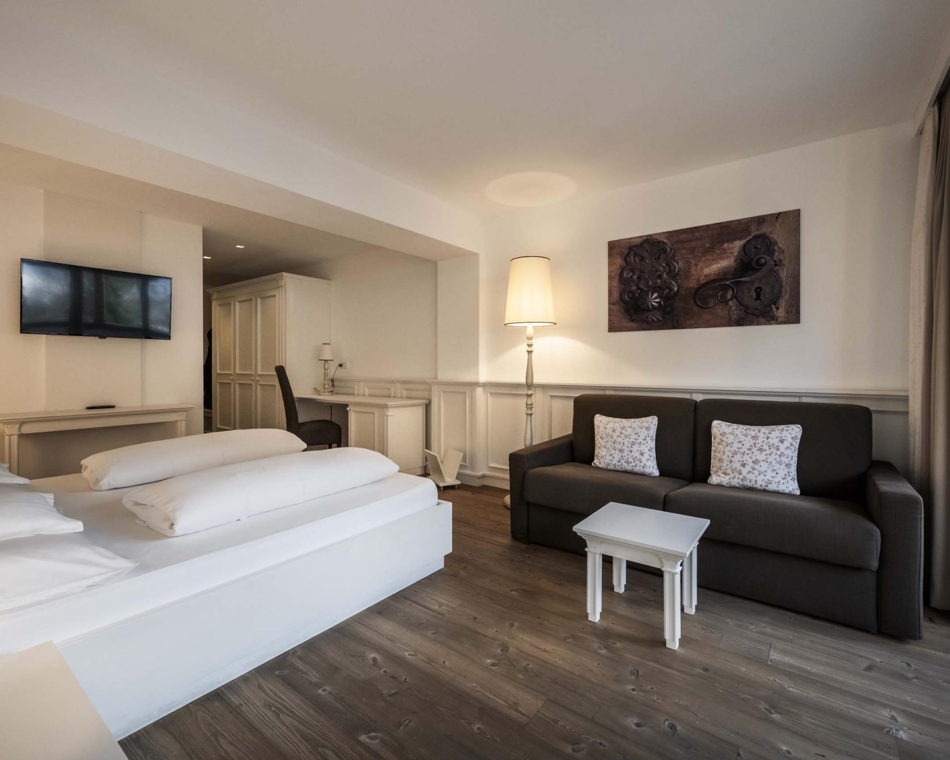 Hotel Monika Zimmer mit Bett, Sofa, Schreibtisch und Fernseher