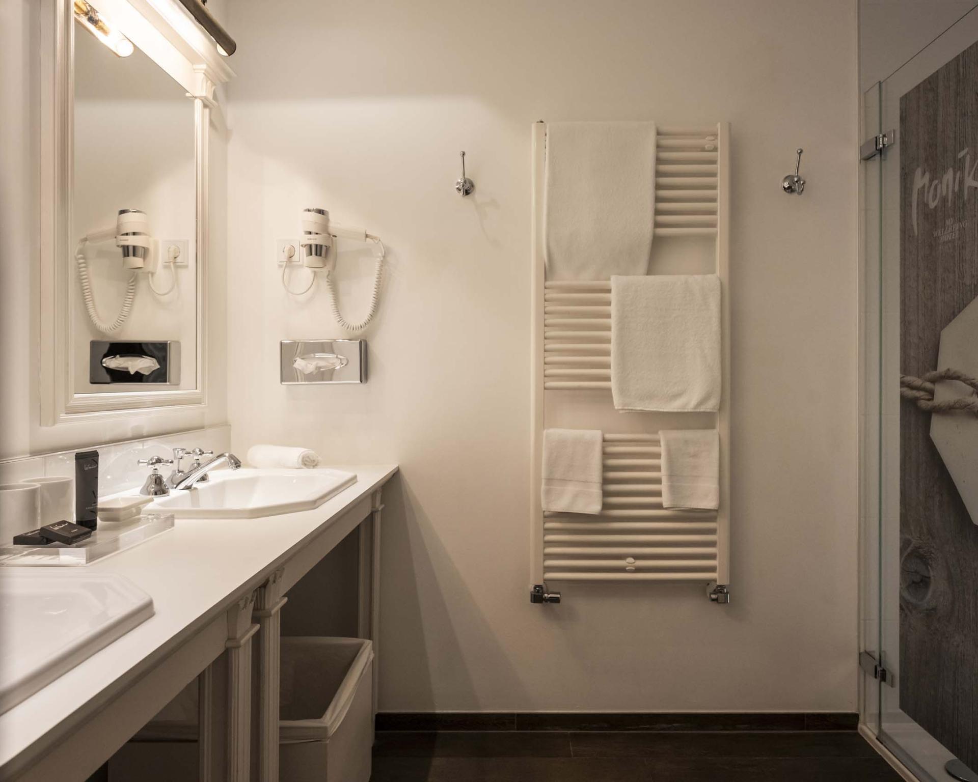 Modernes Badezimmer im Hotel Monika mit Doppelwaschbecken und Handtuchheizung