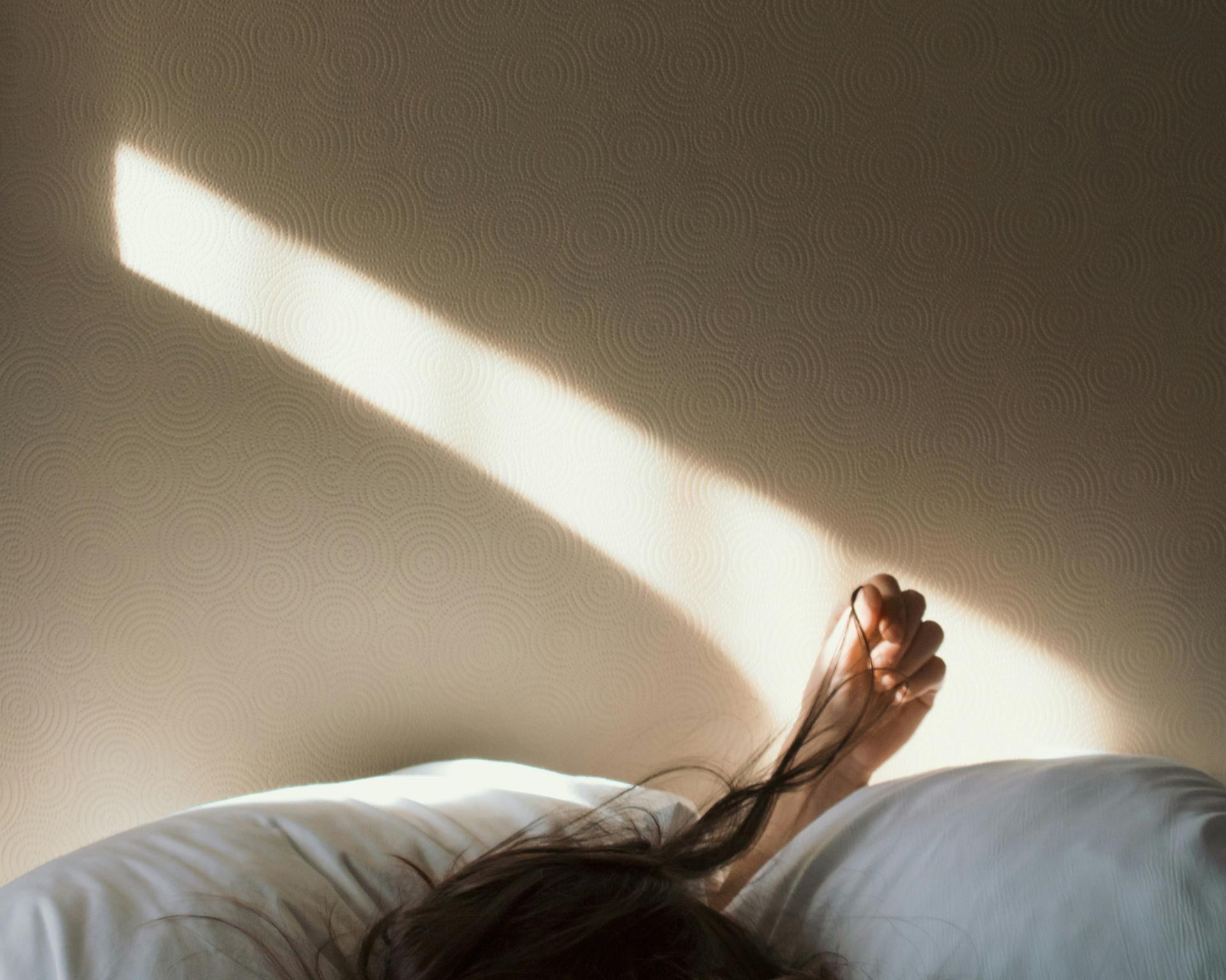 Person liegt schlafend im Bett mit Sonnenlicht und Glockna Atmosphäre