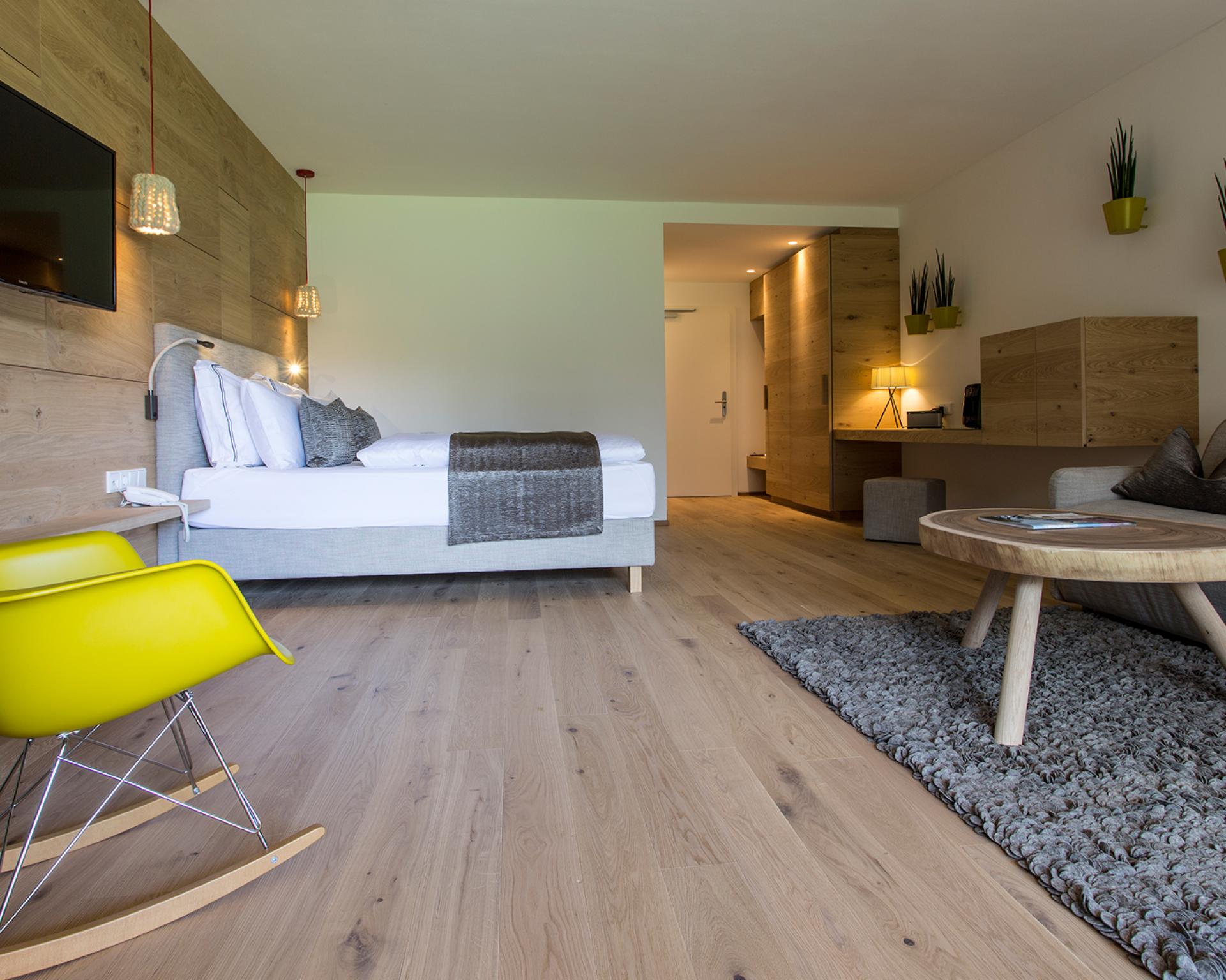 Modernes Hotelzimmer im Hotel Monika mit Bett, Sitzbereich und Holzdekoration