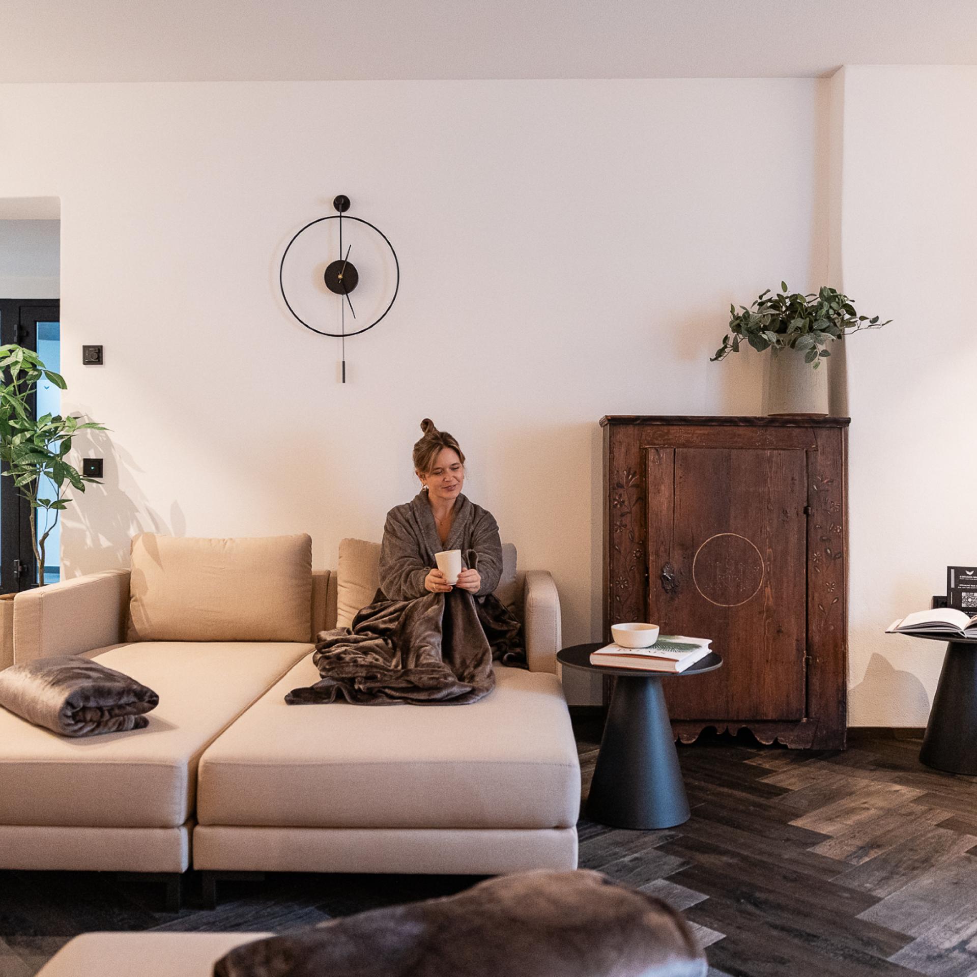 Schwarzer Adler lounge with a woman seated on a light sofa beside a dark wooden cabinet