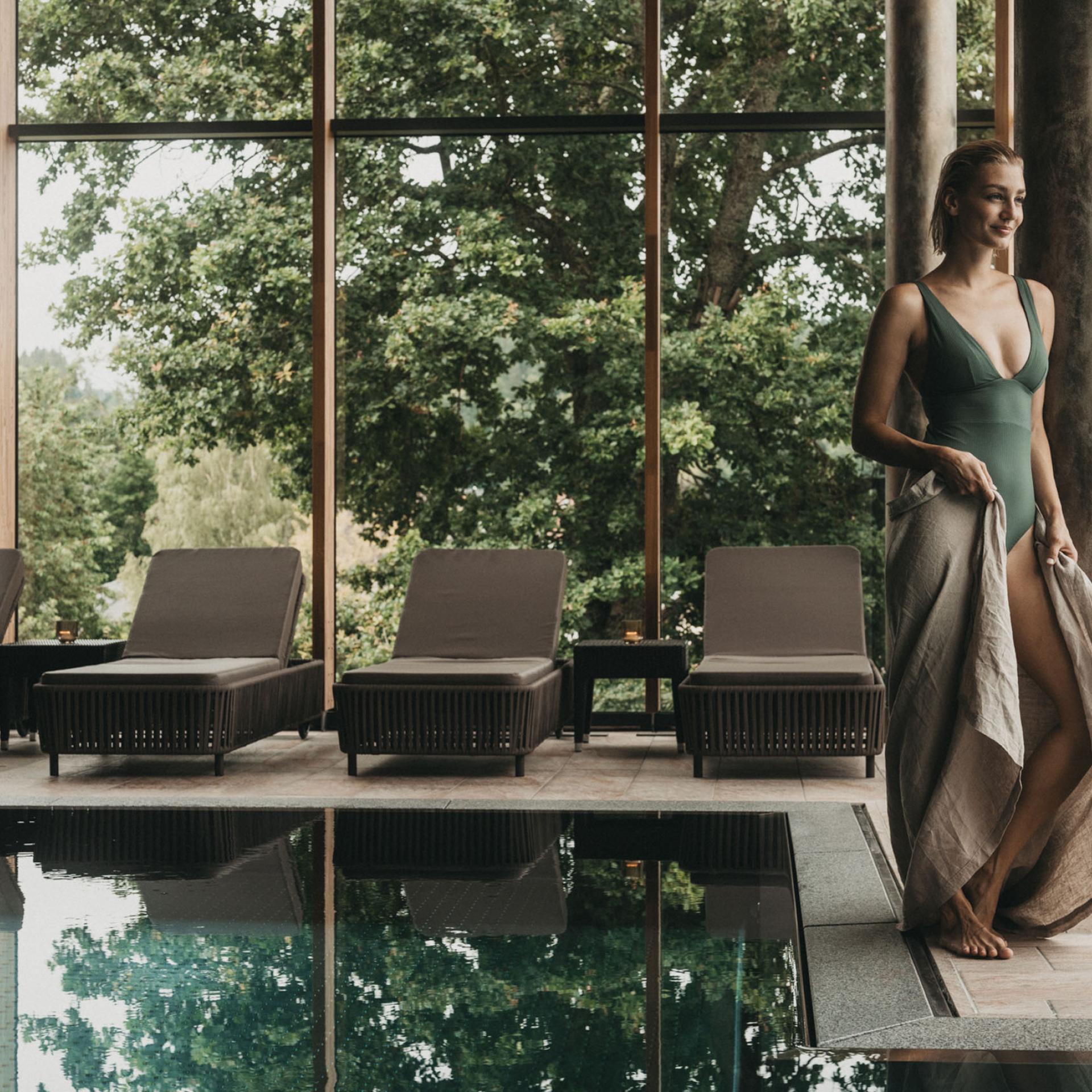 Frau am Pool mit Blick auf Bäume im Eibl-Brunner Spa-Bereich