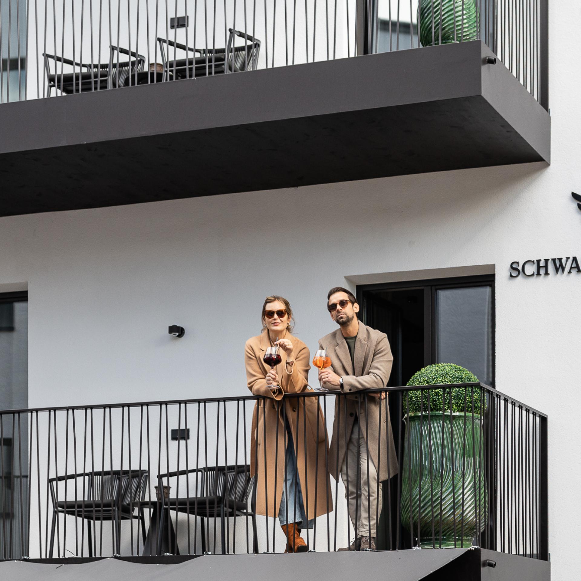 Two people on a balcony beside the Schwarzer Adler sign