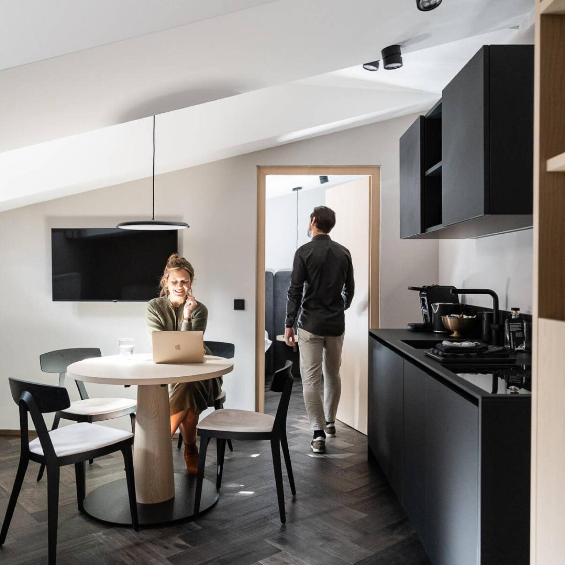 Modern kitchen at Schwarzer Adler with a woman at a laptop and a man in the doorway