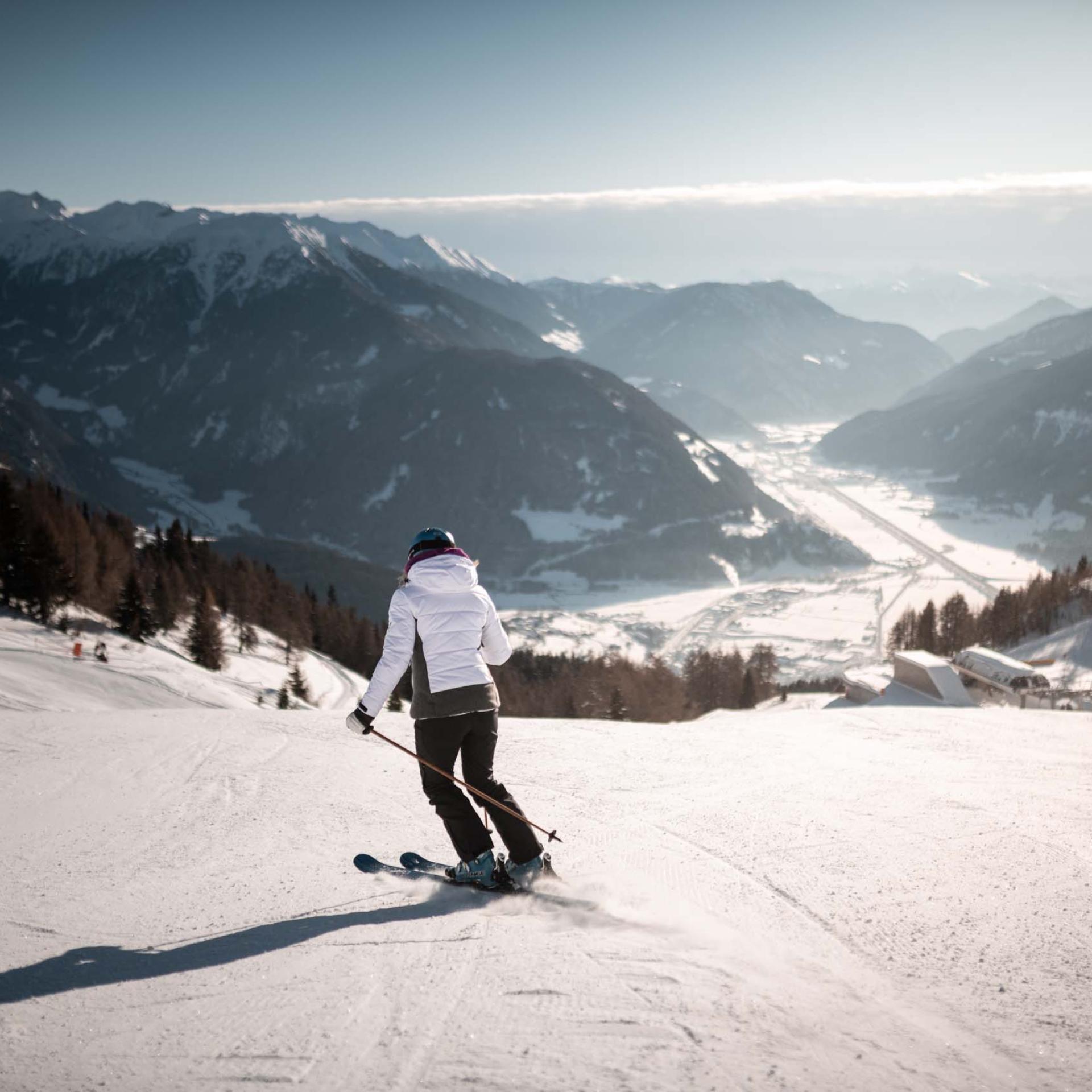 Schwarzer Adler: Skifahrer auf einer verschneiten Piste mit Alpenpanorama