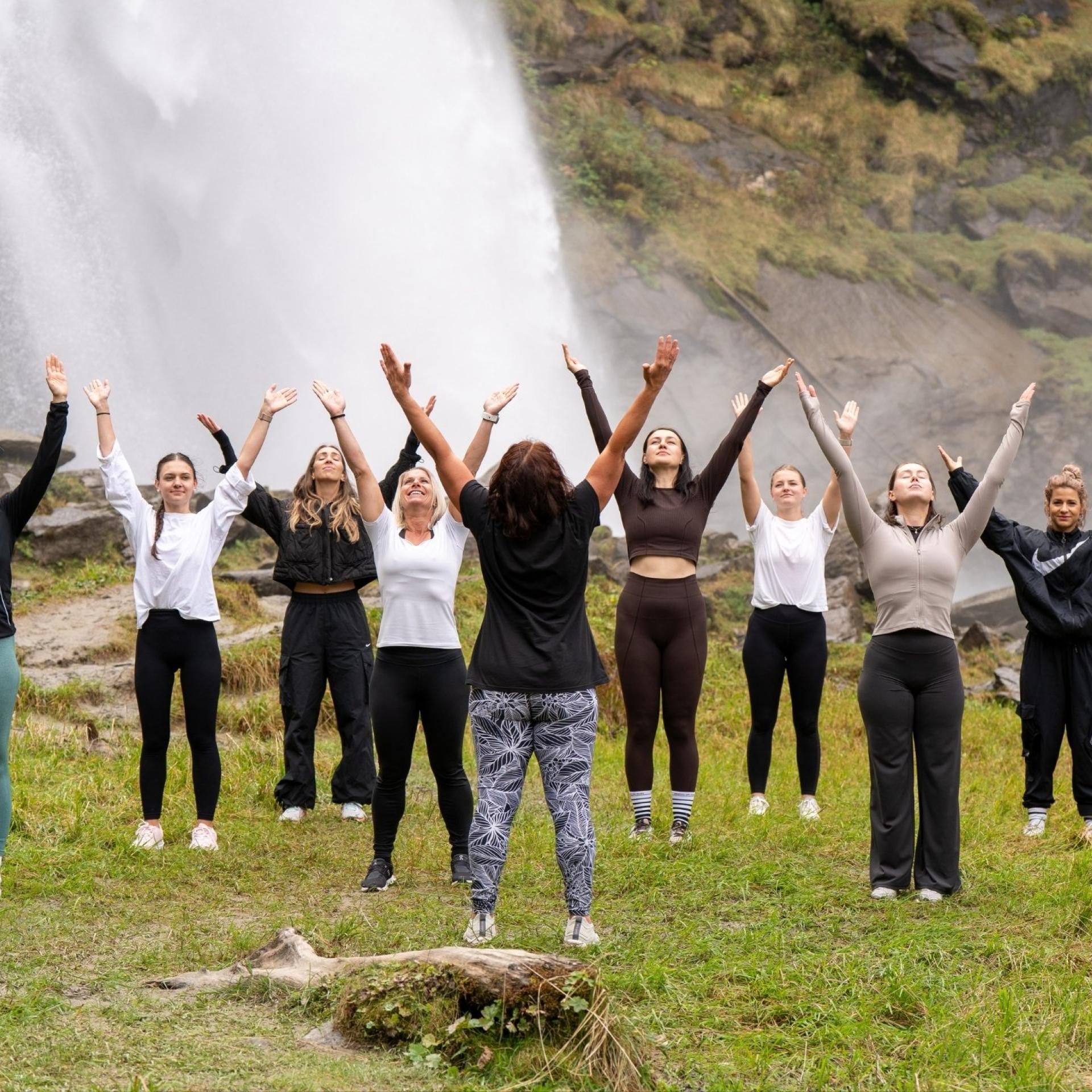 Eine Gruppe praktiziert Yoga nahe dem unteren Wasserfall bei den Krimmler Wasserfällen im Nationalpark Hohe Tauern