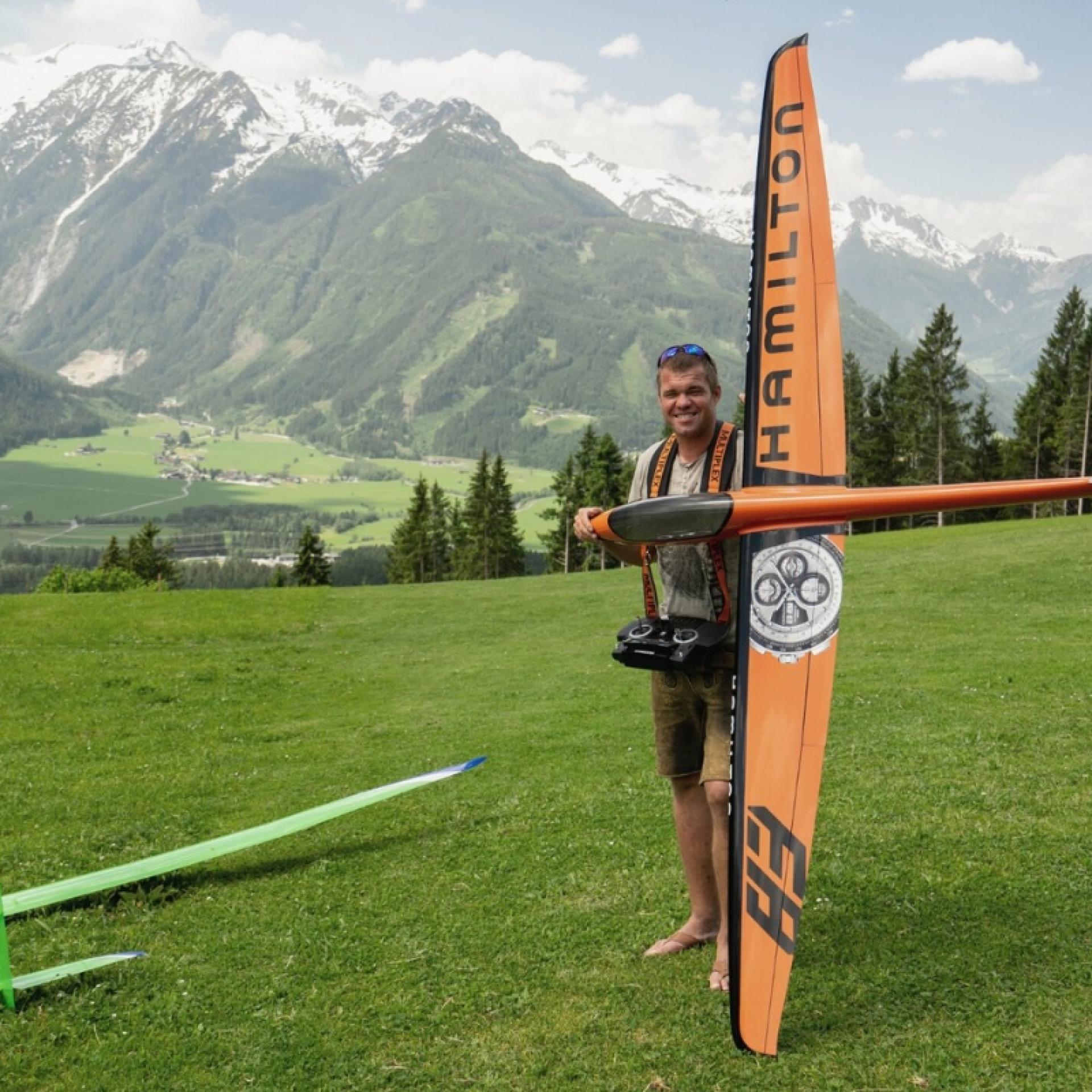 Hotel Gassner **** Superior: Mann hält Modellflugzeug vor Alpenwiesen mit Bergen