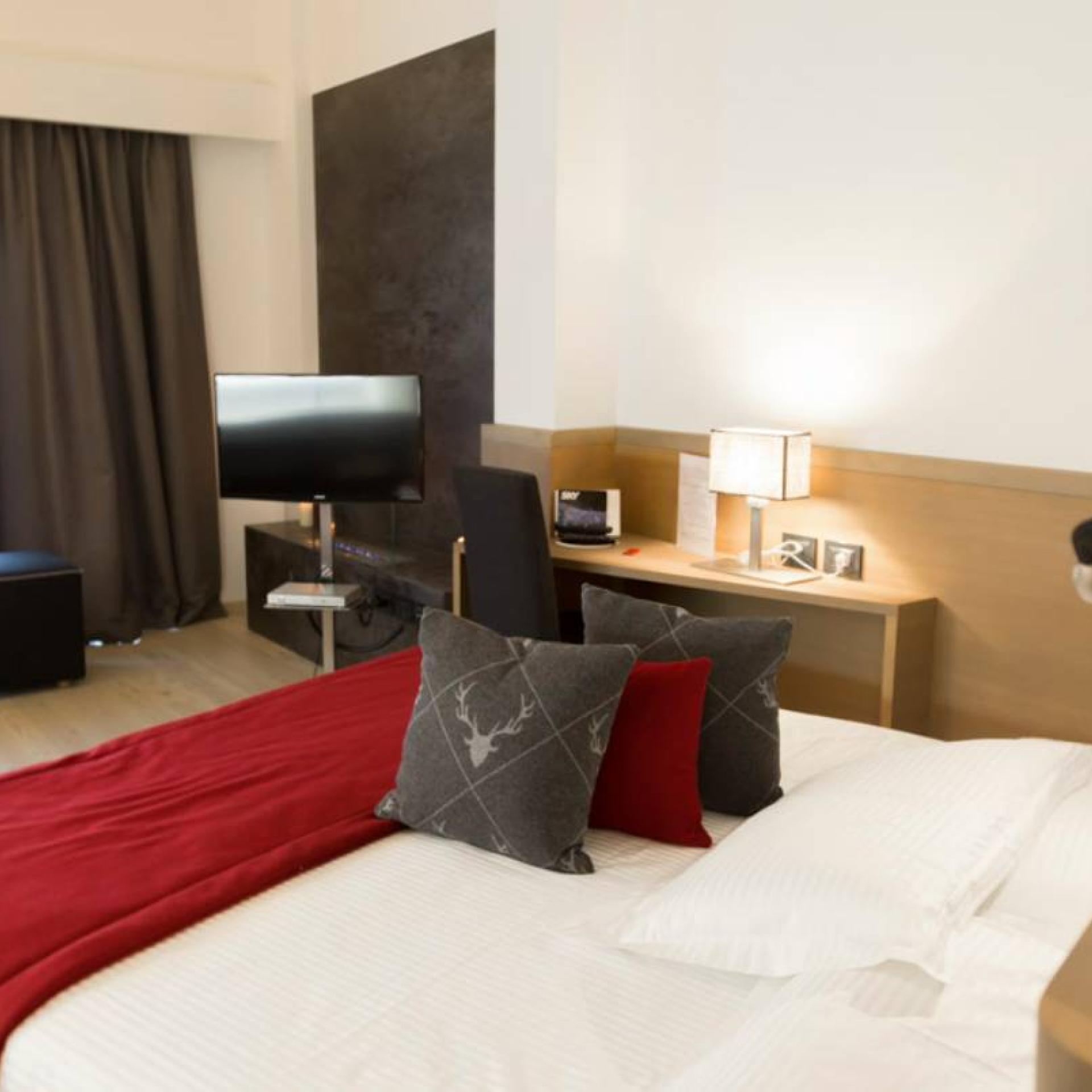 Camera d'hotel moderna all'Hotel San Giacomo con copriletto rosso e TV
