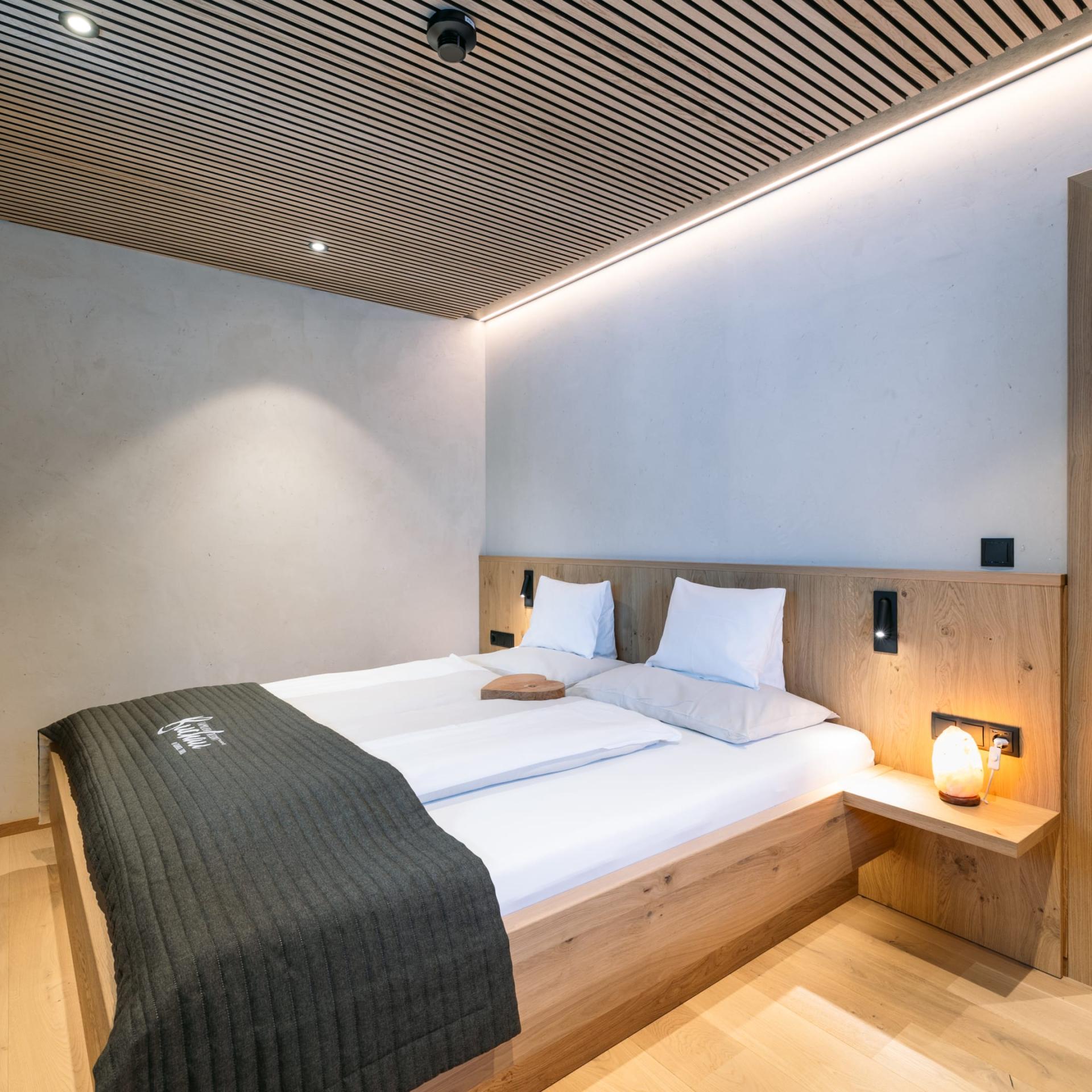Gemütliches Schlafzimmer im Familienresort Buchau mit Doppelbett und Holzmöbeln